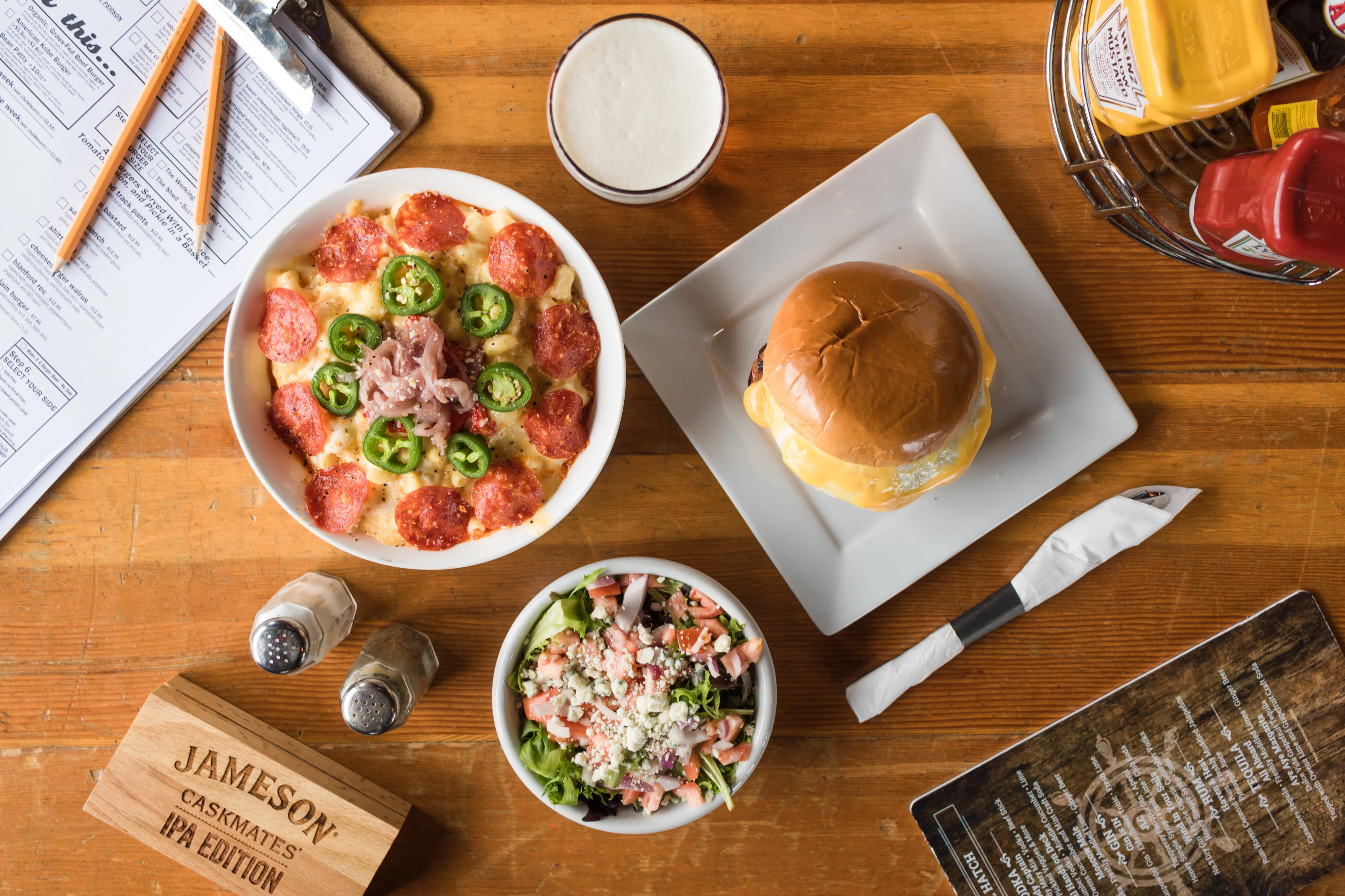 Delicious pepperoni pizza with jalapeños and a cheeseburger on a wooden table