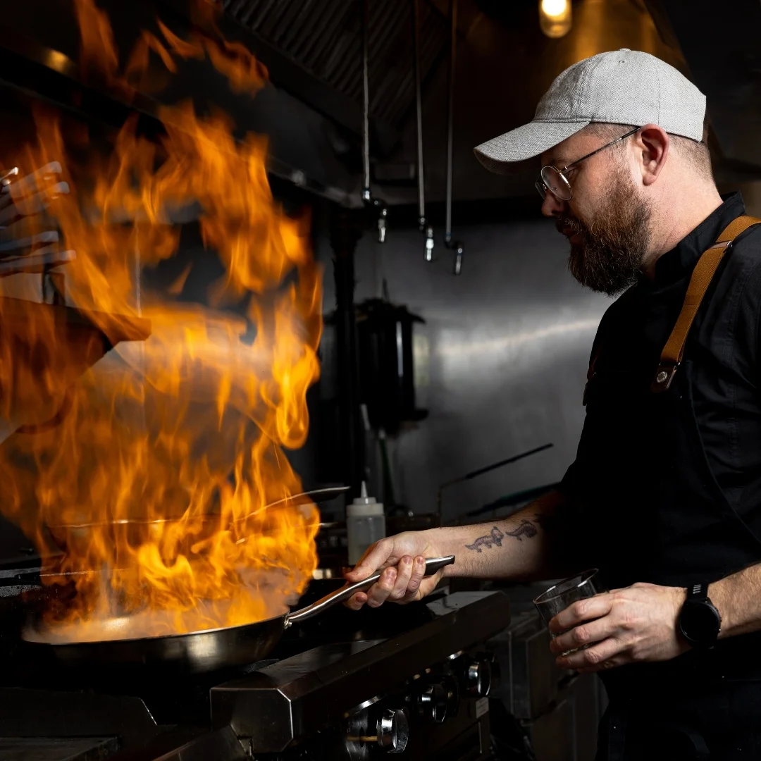 Chef preparing a dish with an open flame at Bass Street restaurant in Moline, IL