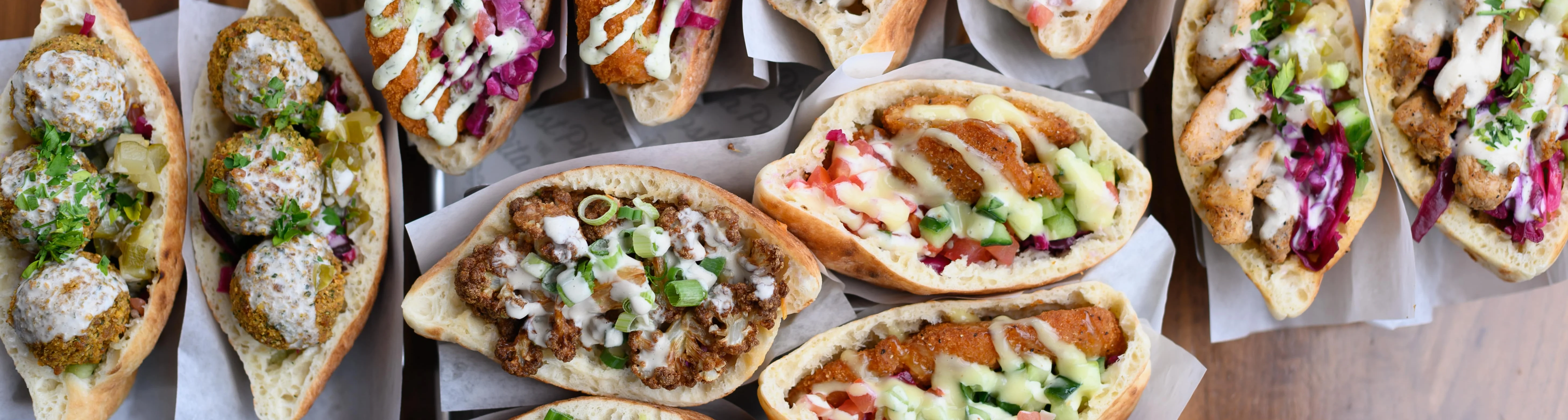 A group of people waiting for their food in front of the Pita Post Food Truck in Michigan