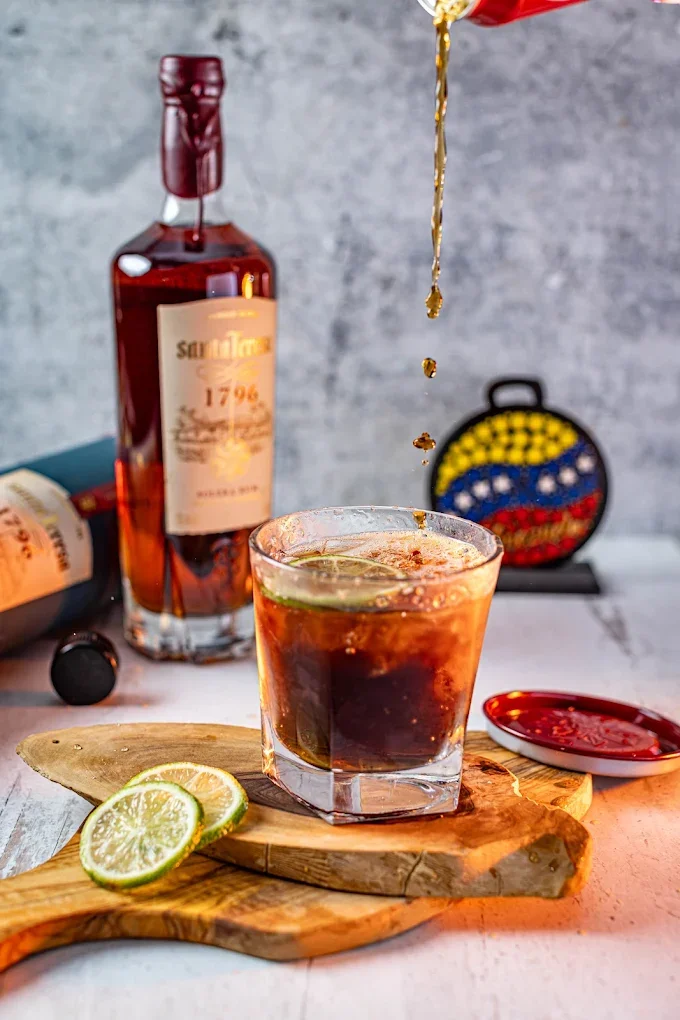 A classic Cuba Libre cocktail being prepared with premium Santa Teresa 1796 Venezuelan rum at the bar at El Budare Cafe.