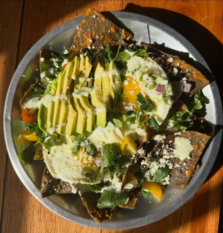 Plate of Mexican chilaquiles topped with avocado and eggs