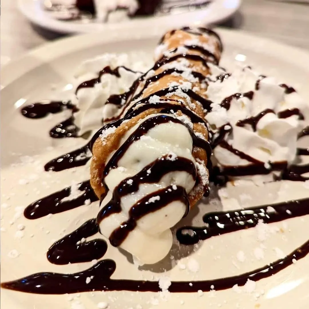 Italian cannoli drizzled with chocolate sauce and whipped cream