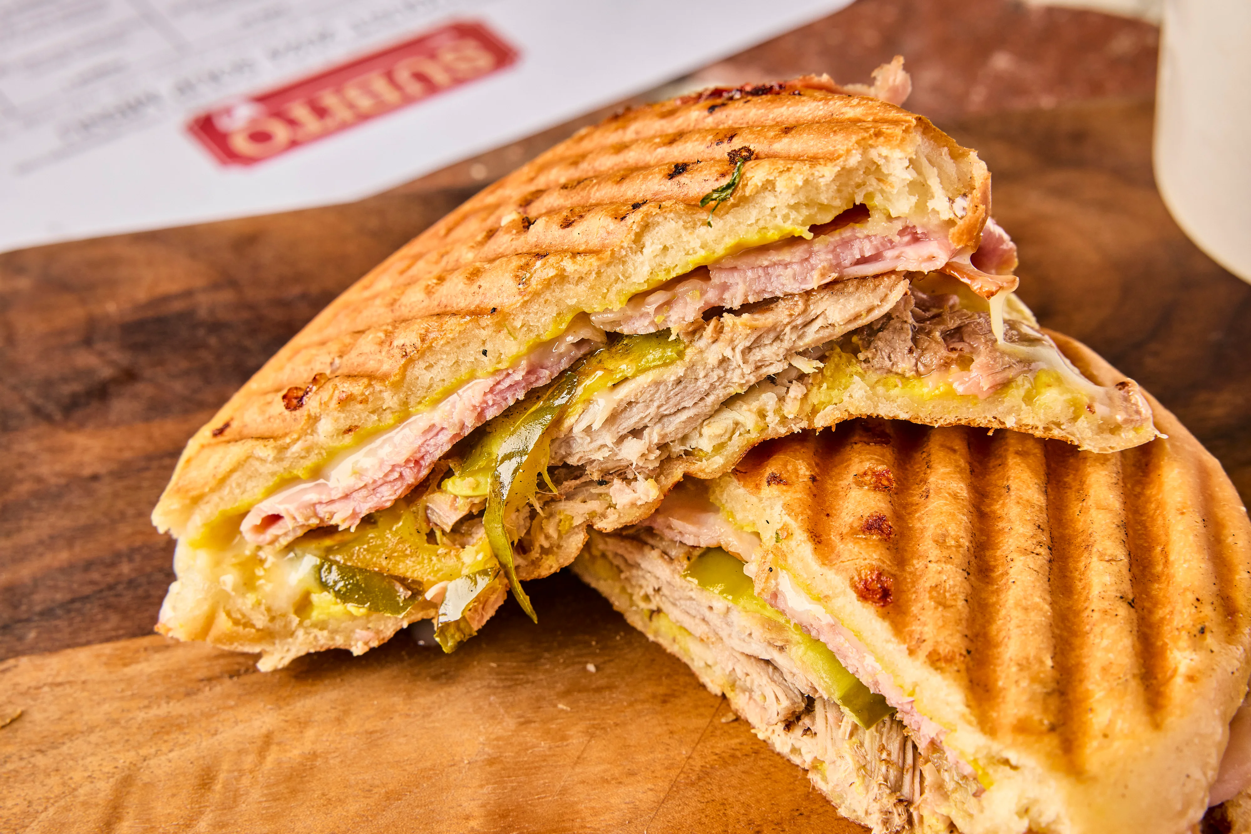The Cuban has roasted pork shoulder w/ham, Swiss cheese, yellow mustard, & house pickles on our pressed soft bun.