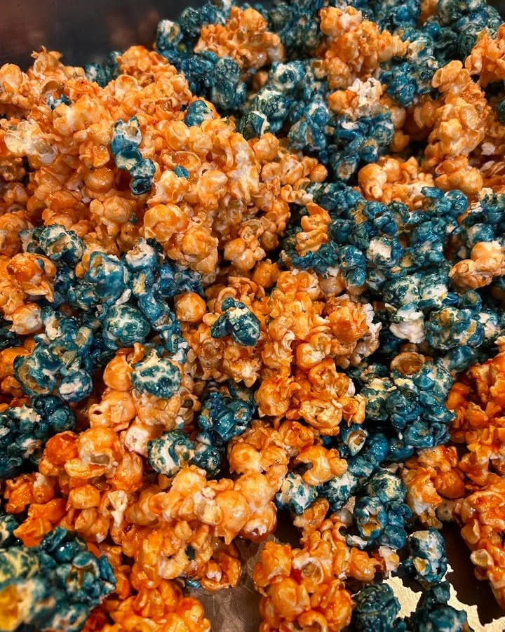 A large serving tray filled with a colorful mix of popcorn varieties, including yellow, white, and caramel-coated pieces.