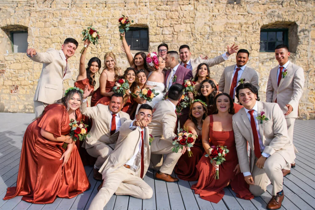 Joyful wedding party celebrating outdoors with vibrant attire and floral arrangements