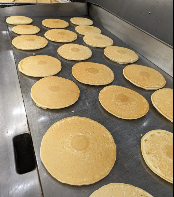 Golden pancakes cooking on a griddle