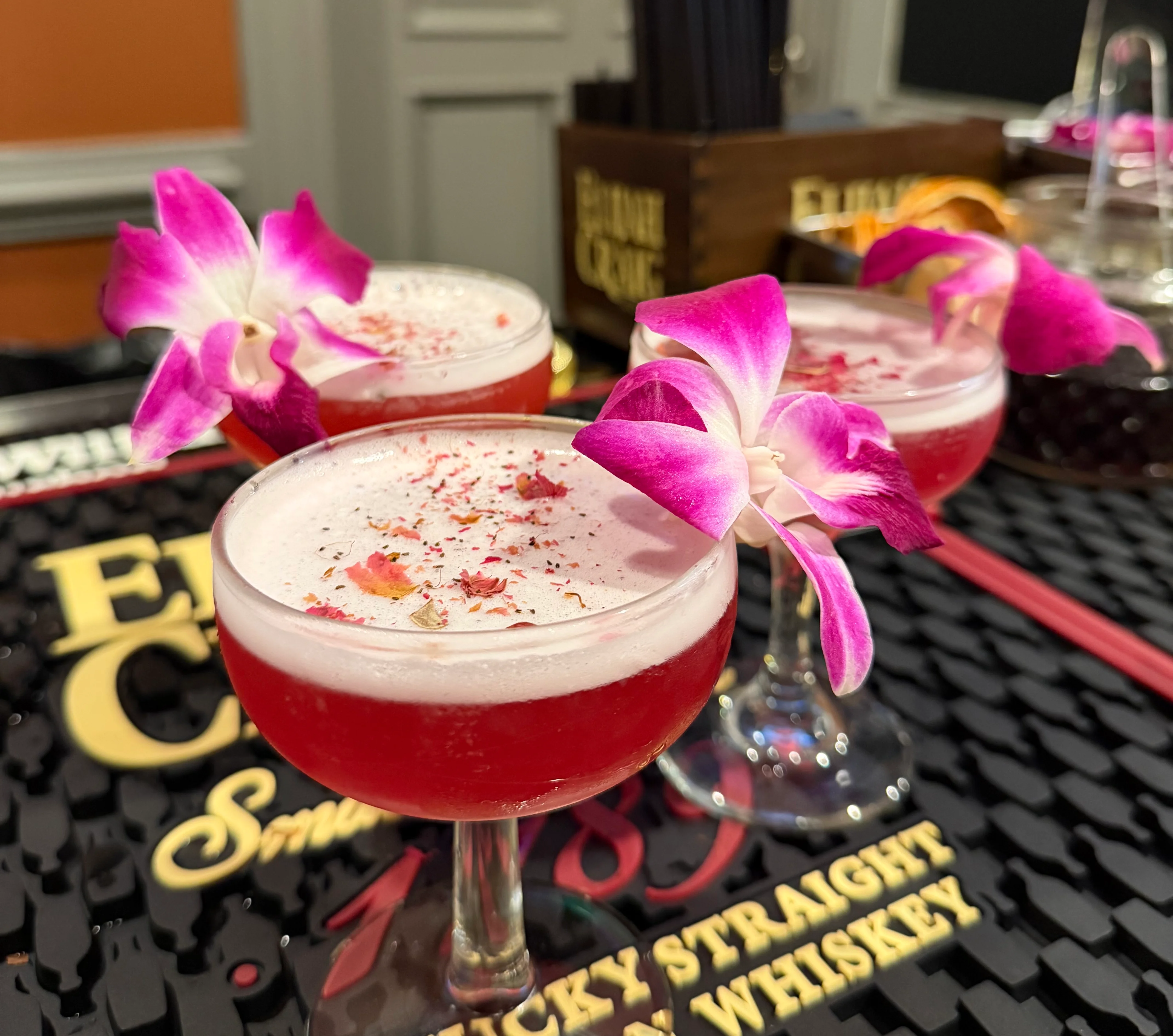Colorful cocktails garnished with orchids on a bar counter