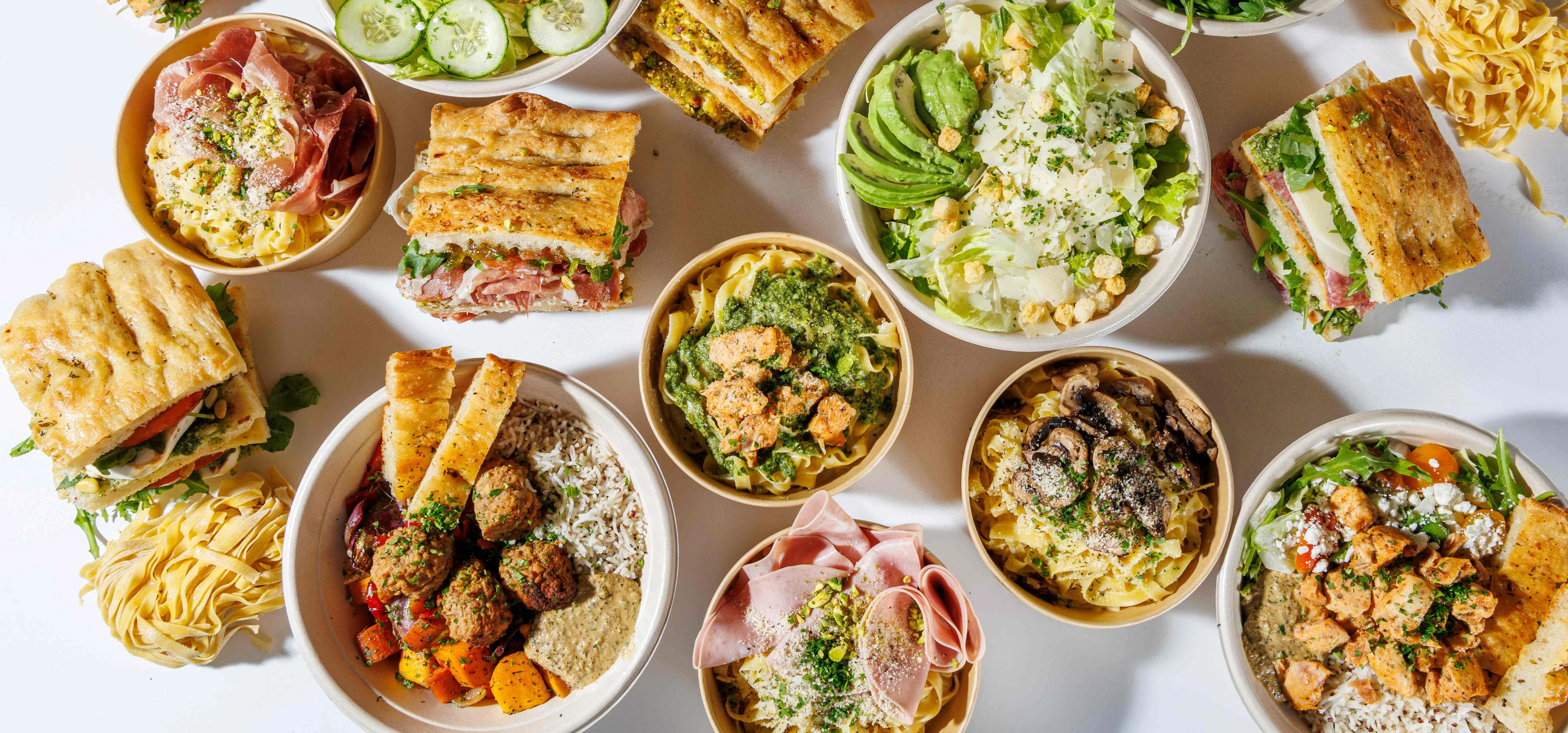 Assorted Italian pasta dishes and sandwiches on a white table