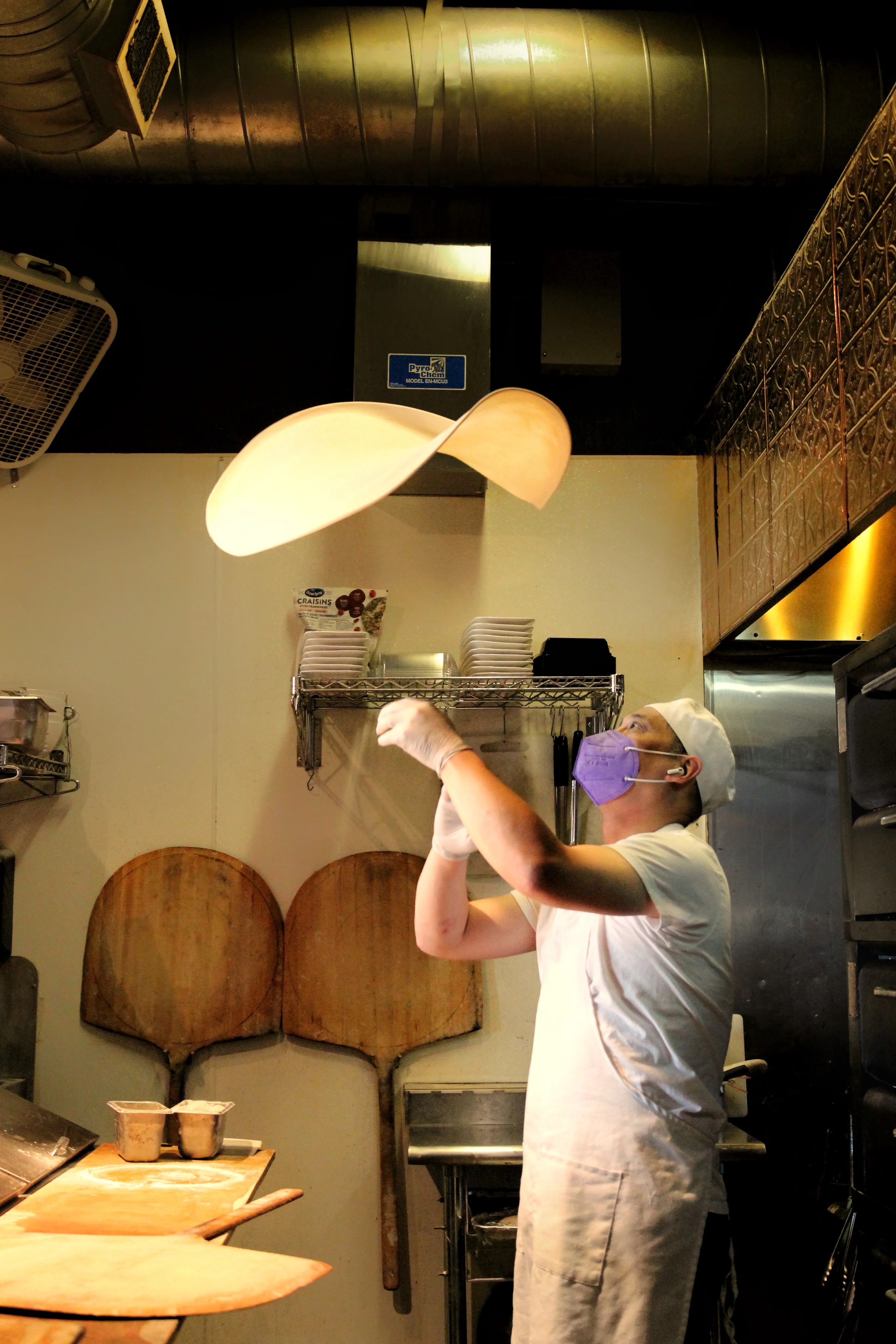 Chef tossing pizza dough in a vibrant kitchen