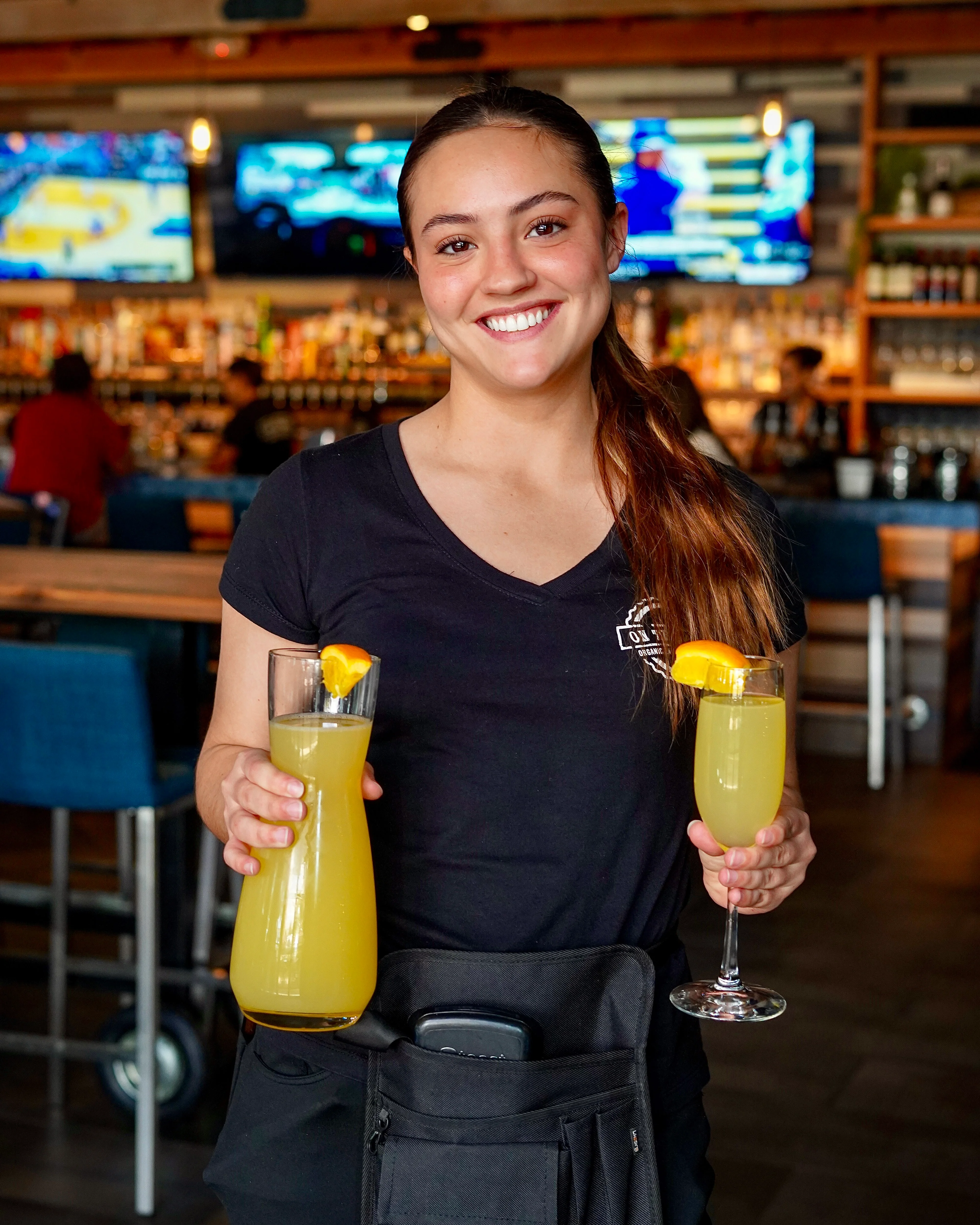 Server presenting refreshing cocktails at a lively bar