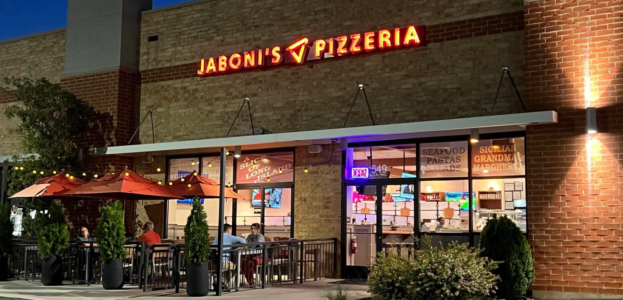 Exterior view of Jaboni's Pizzeria with outdoor seating at night.