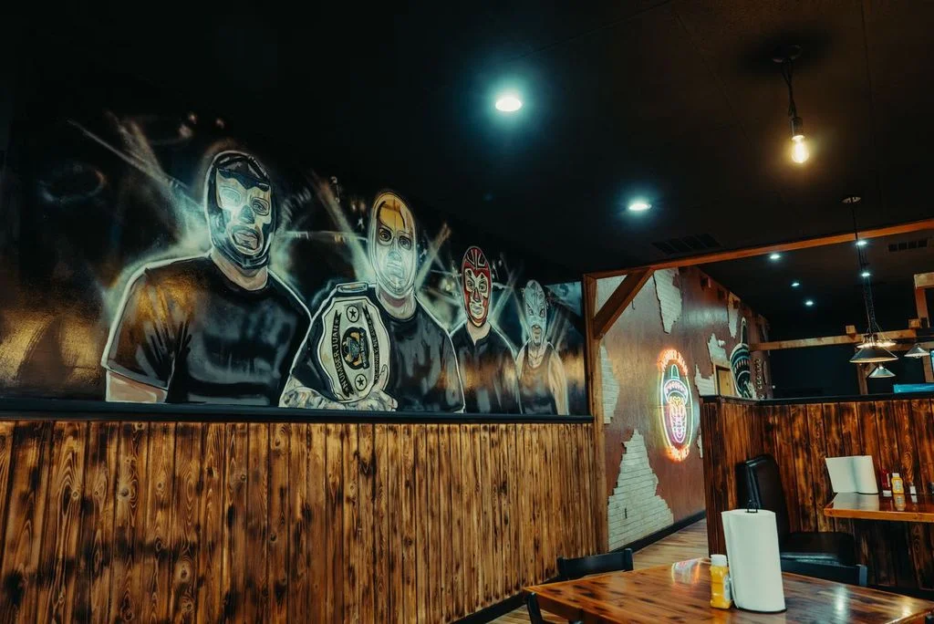 Vibrant mural in a rustic restaurant featuring masked wrestlers