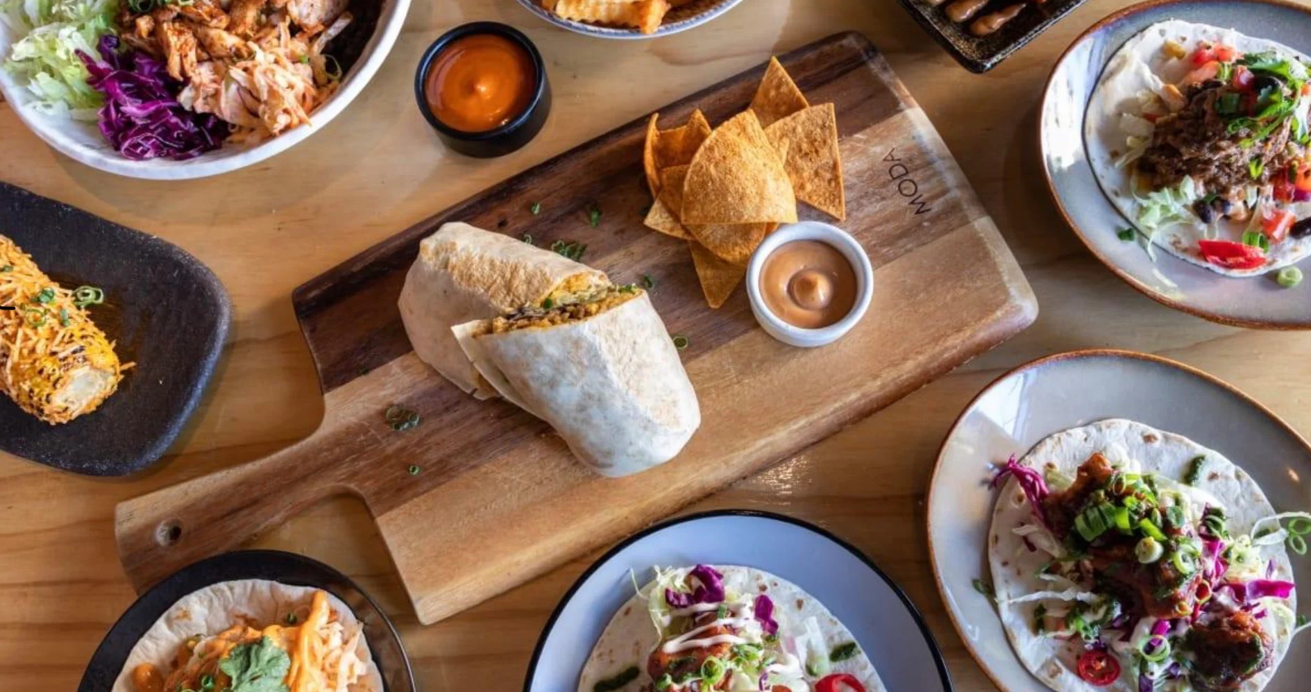 Delicious Mexican burrito and tacos served on a wooden platter