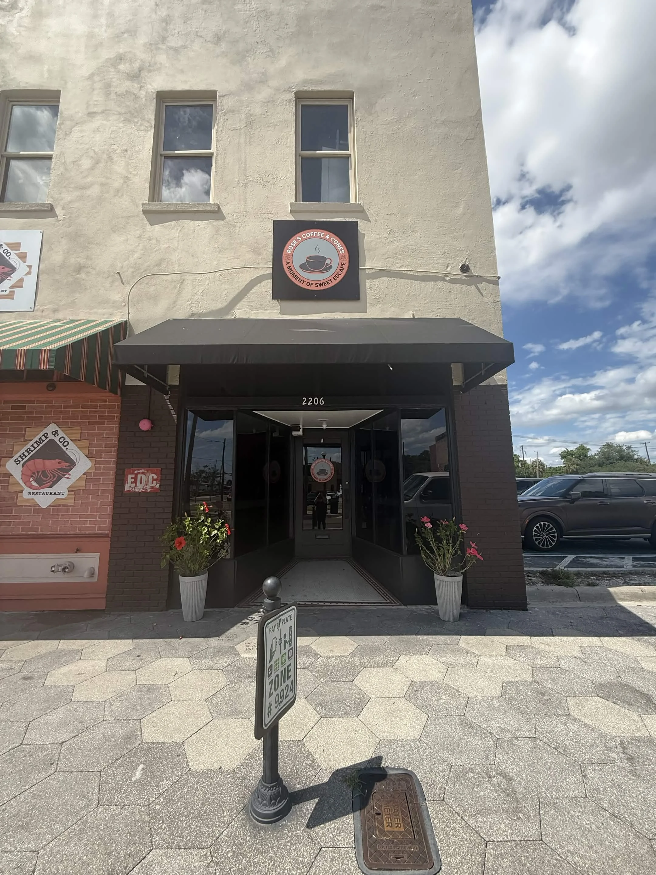 Entrance of a coffee shop with a sign and flower pots.