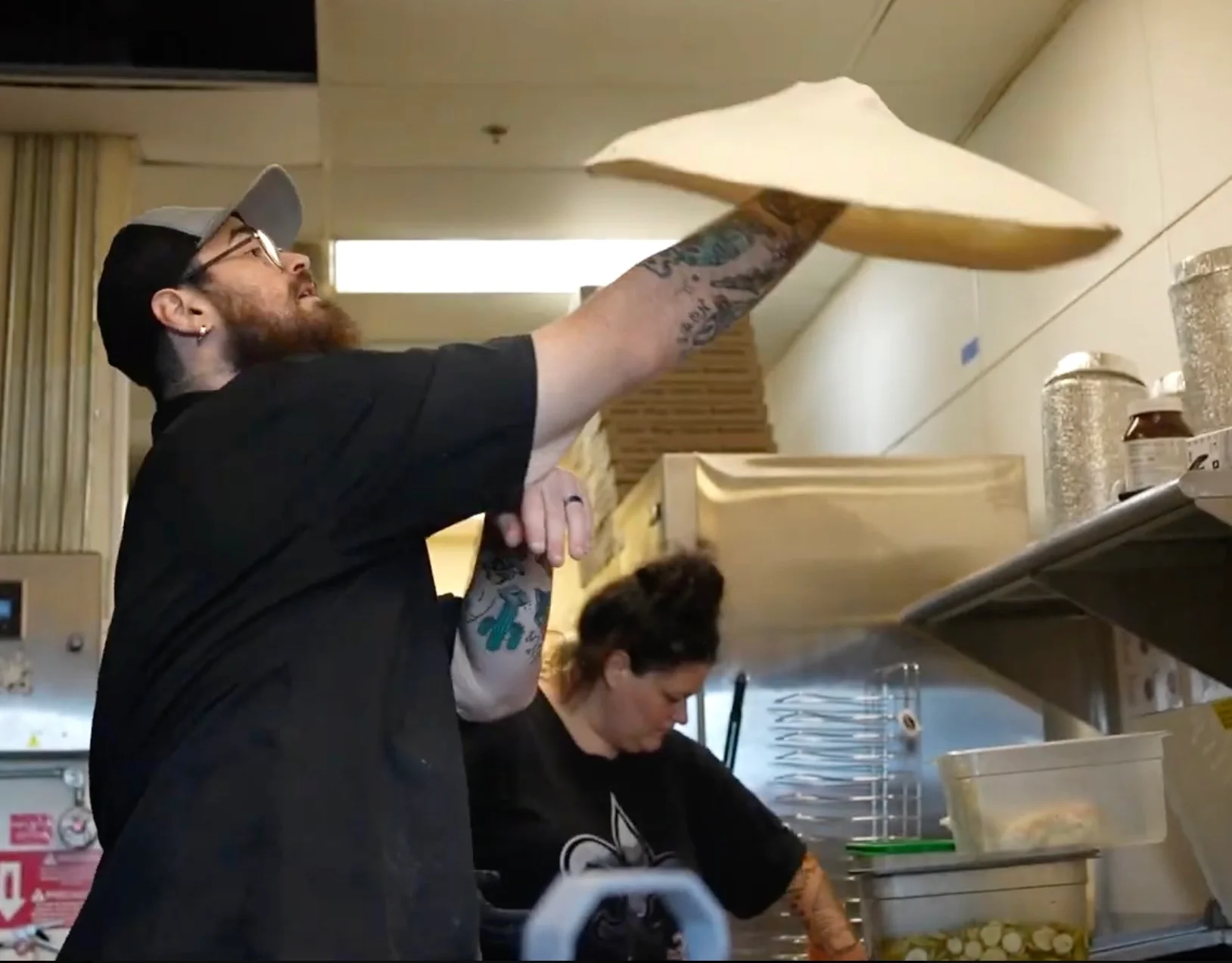 Pizza chef tossing dough in a vibrant kitchen