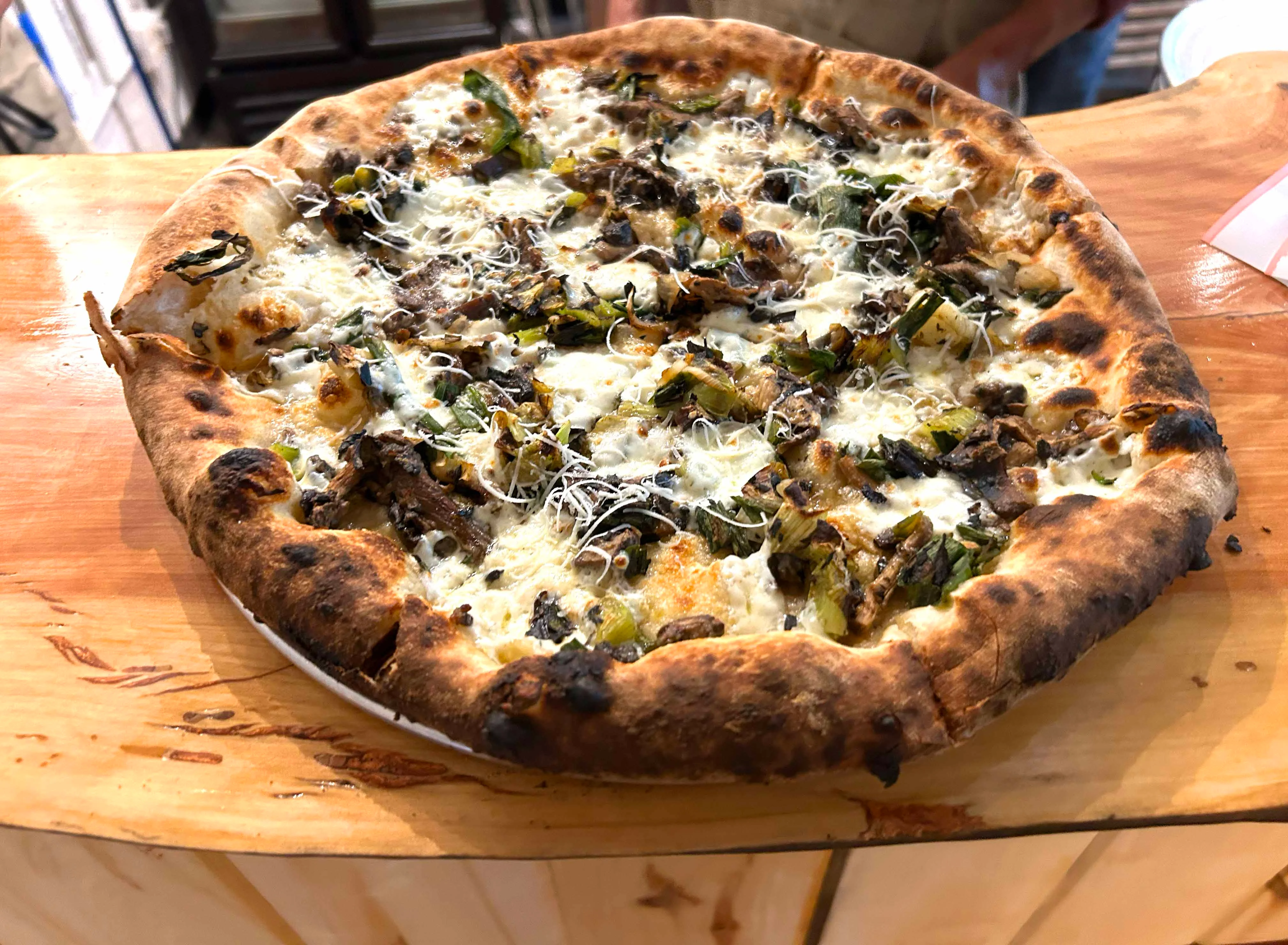 Wood-fired pizza topped with mushrooms and greens