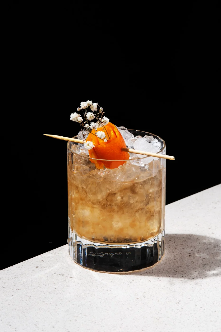 Craft cocktail with orange garnish and flowers