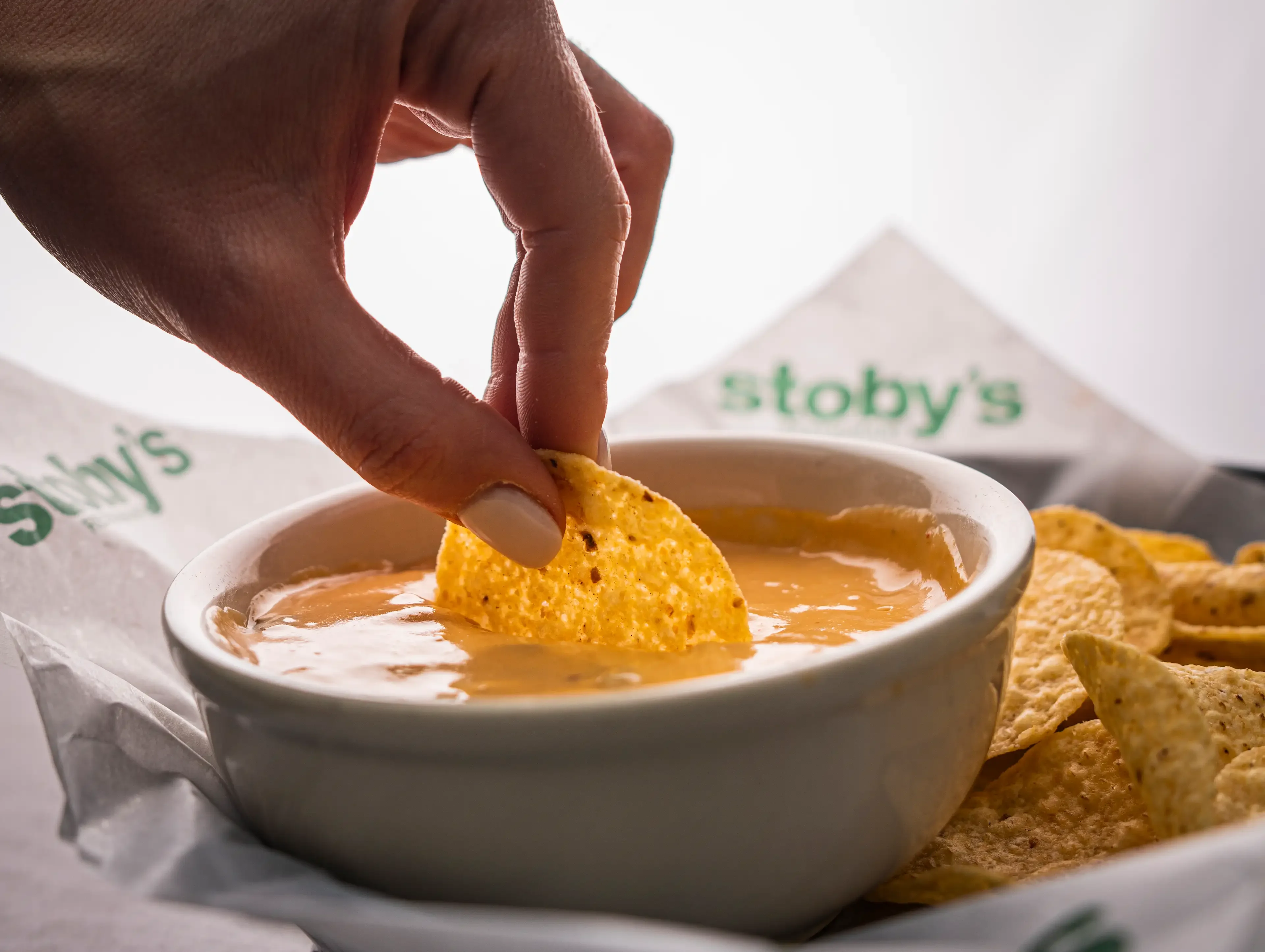 A person dipping into thick, rich cheese dip