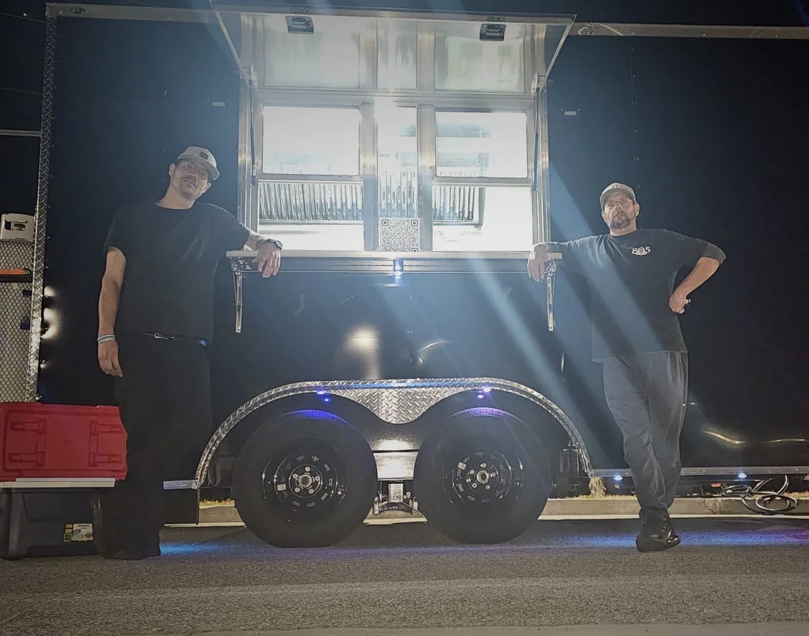 Food truck owners posing in front of their mobile kitchen at night