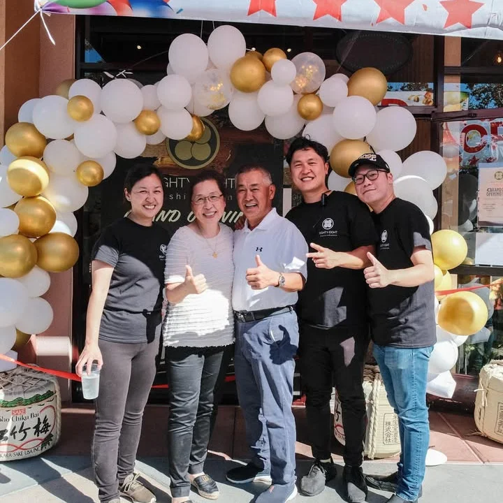 Grand opening celebration with staff and guests at a restaurant entrance