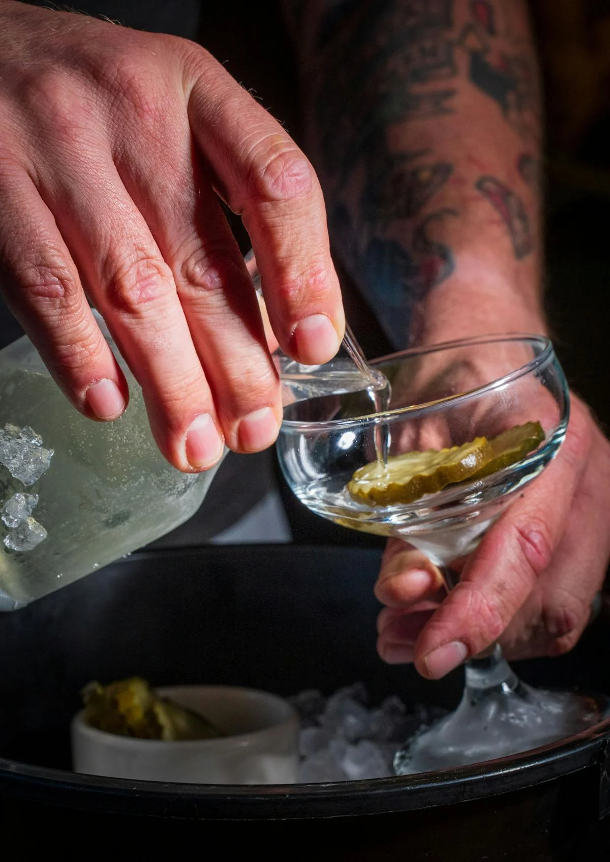 Bartender pouring a cocktail with pickles at a trendy bar