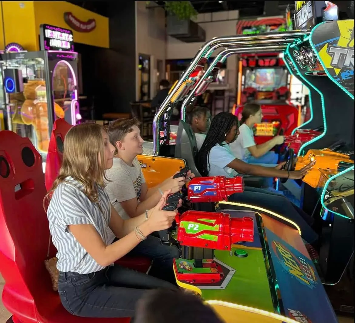 Group of kids enjoying arcade games at a fun center.