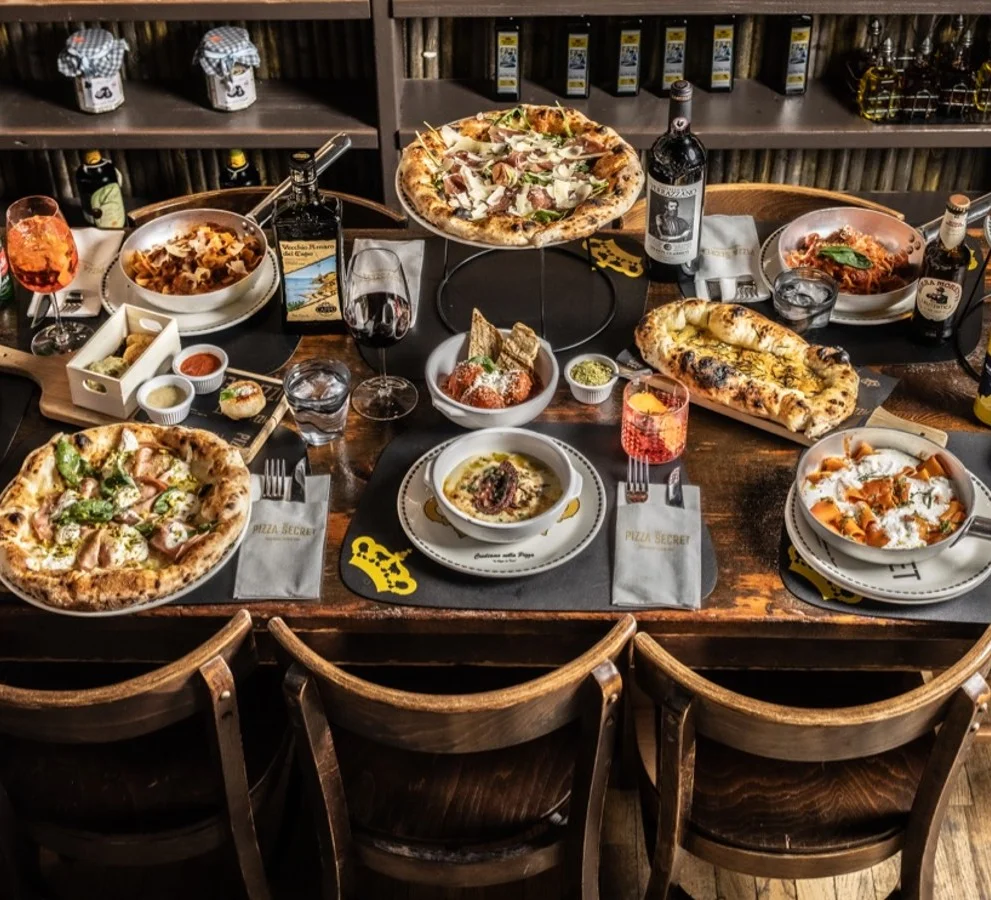 Full table crowded with dishes and diners at Pizza Secret
