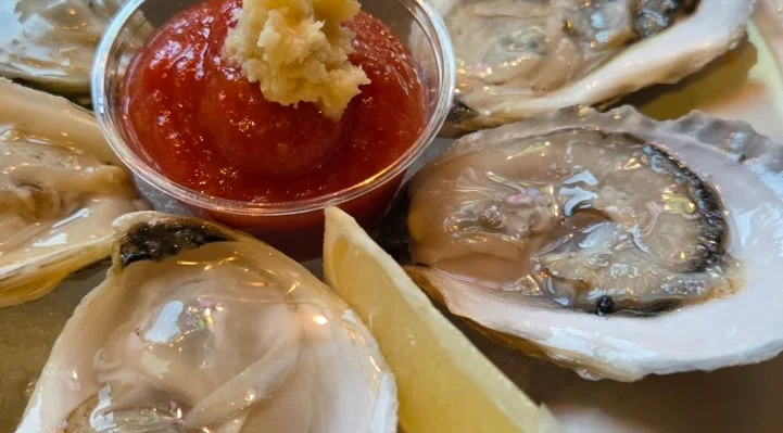 Freshly shucked oysters on a plate with cocktail sauce and lemon