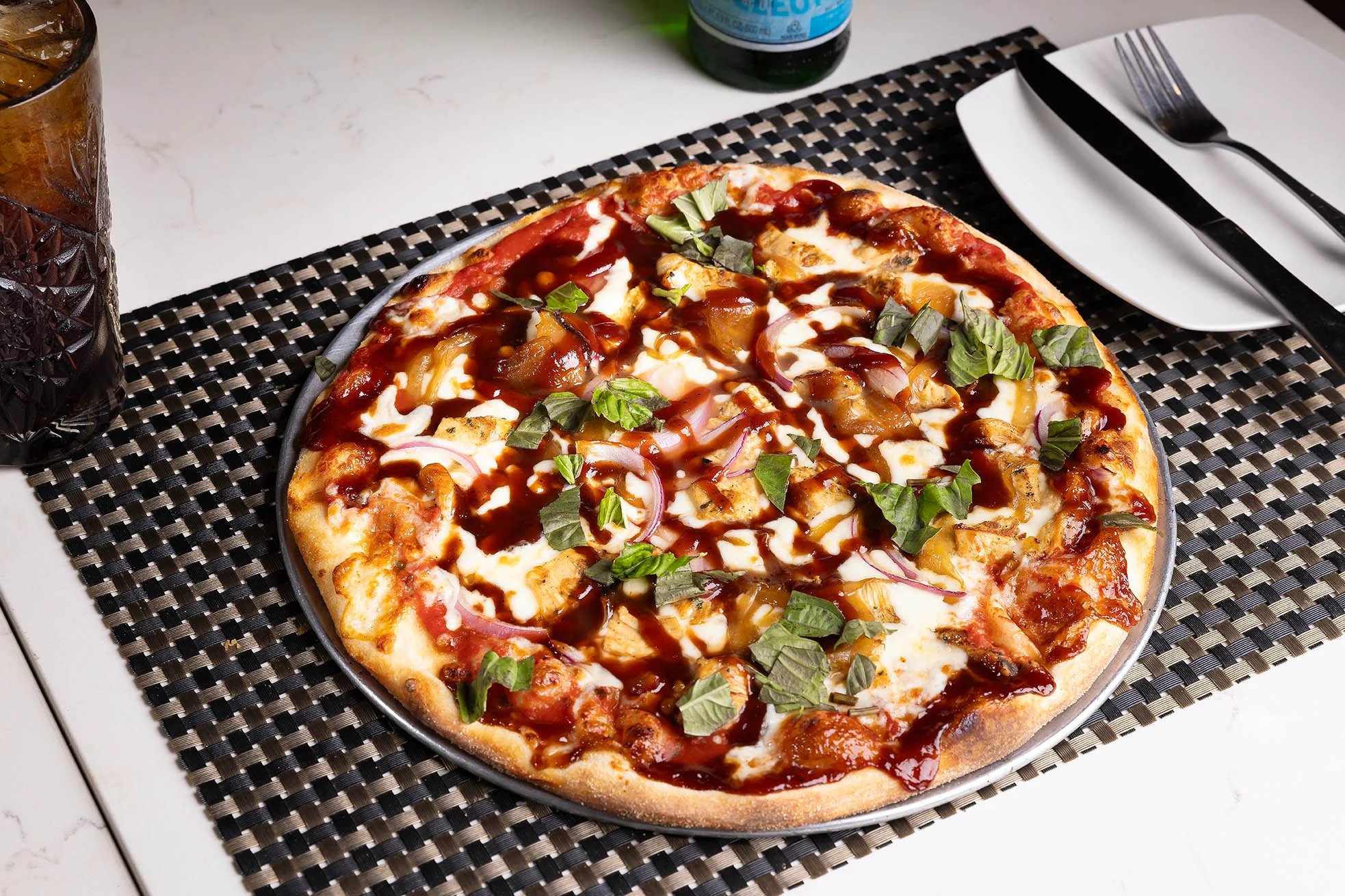Cucina speciality pizza with vegetables and BBQ drizzle