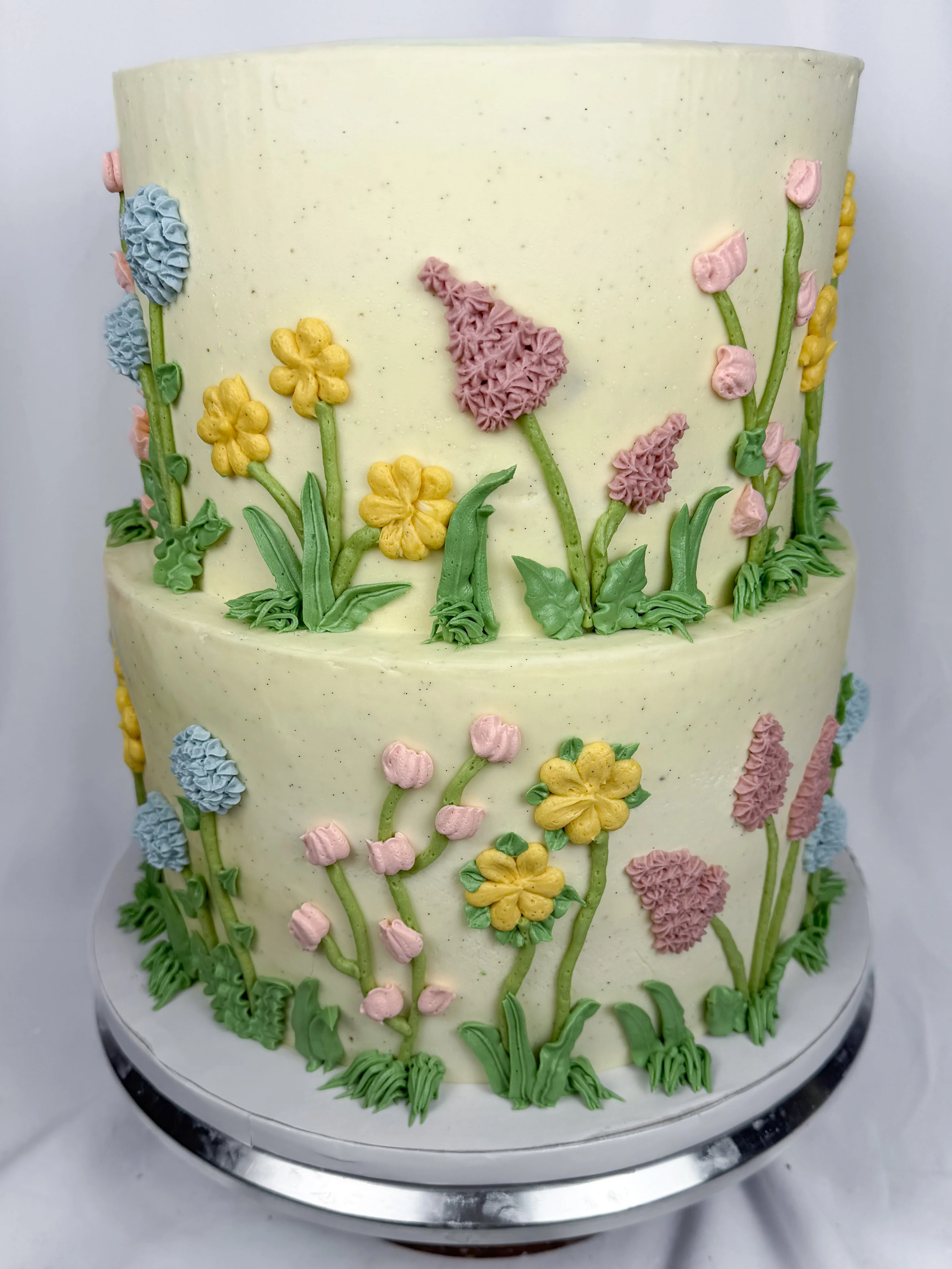 Two-tiered cake decorated with colorful buttercream flowers.