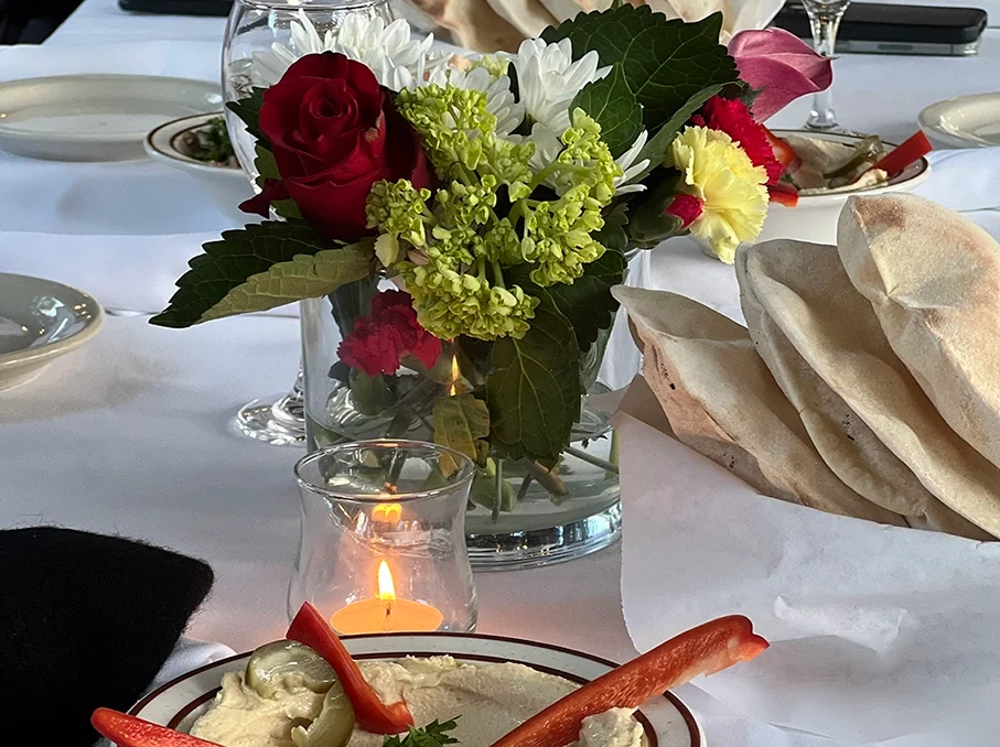 Elegant restaurant table with flowers, wine glasses, bread, and diners