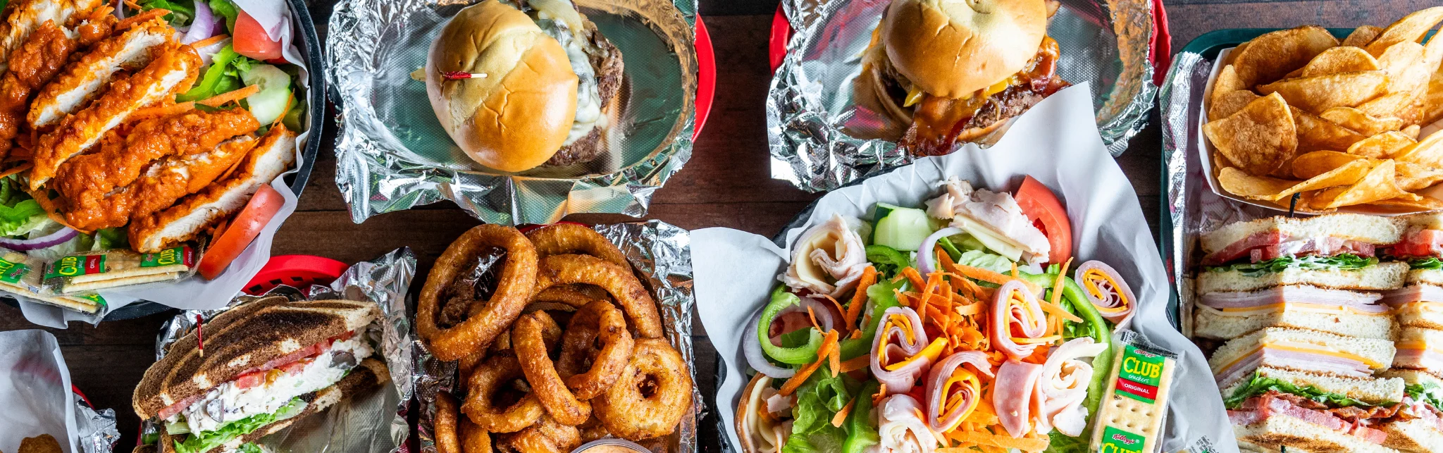 Assorted American sandwiches and sides on a wooden table