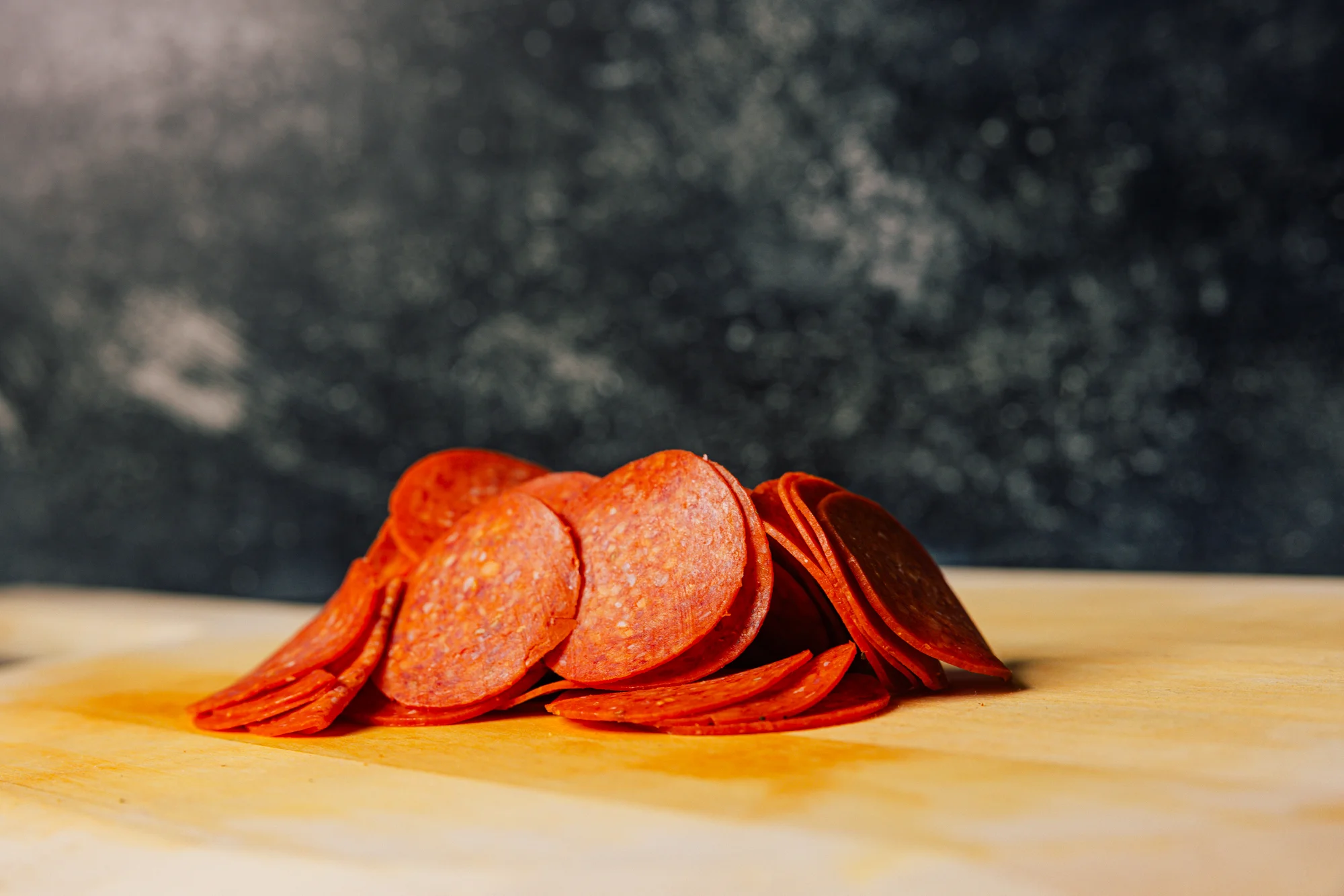 Sliced pepperoni on a wooden cutting board