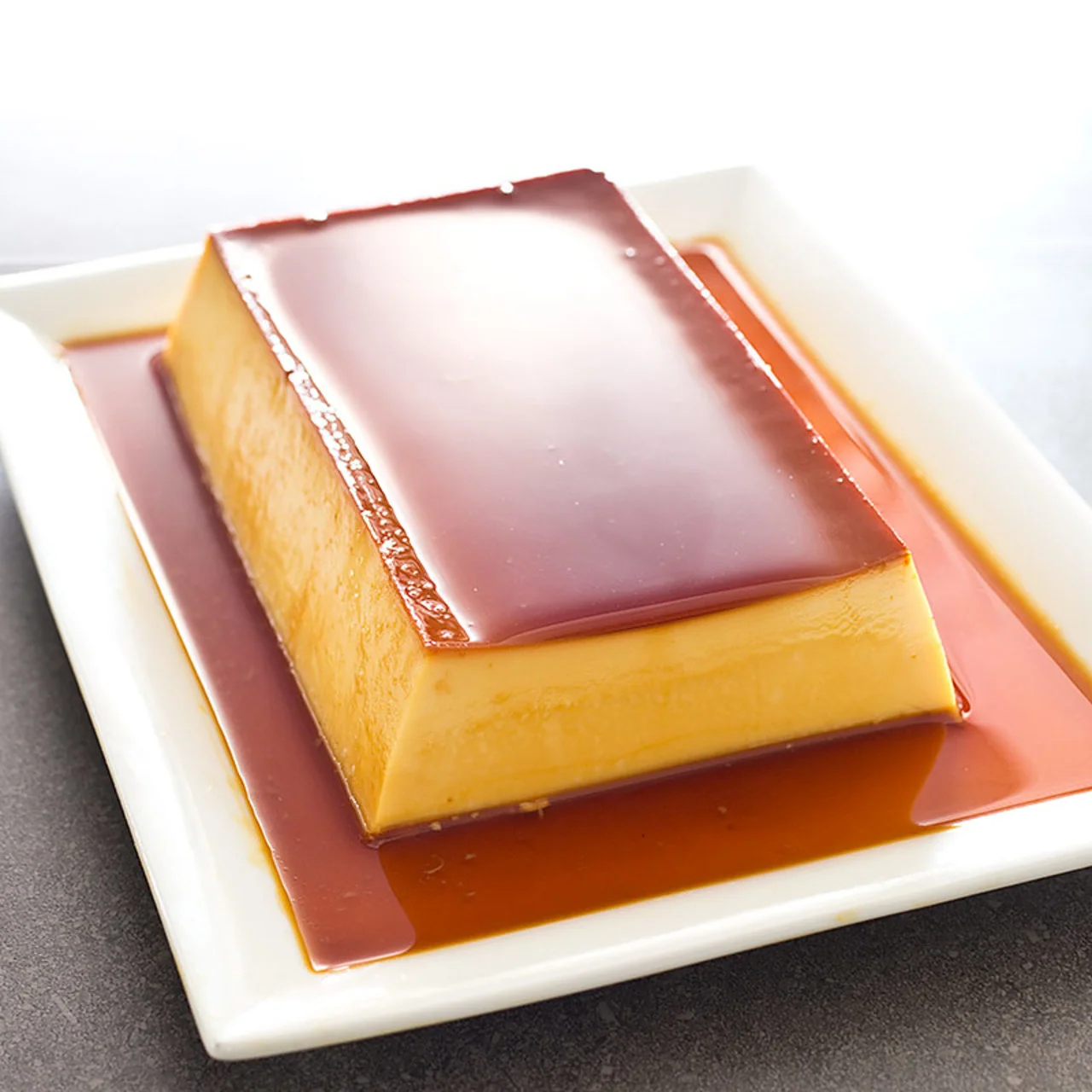 Delicious flan dessert with caramel sauce on a white plate