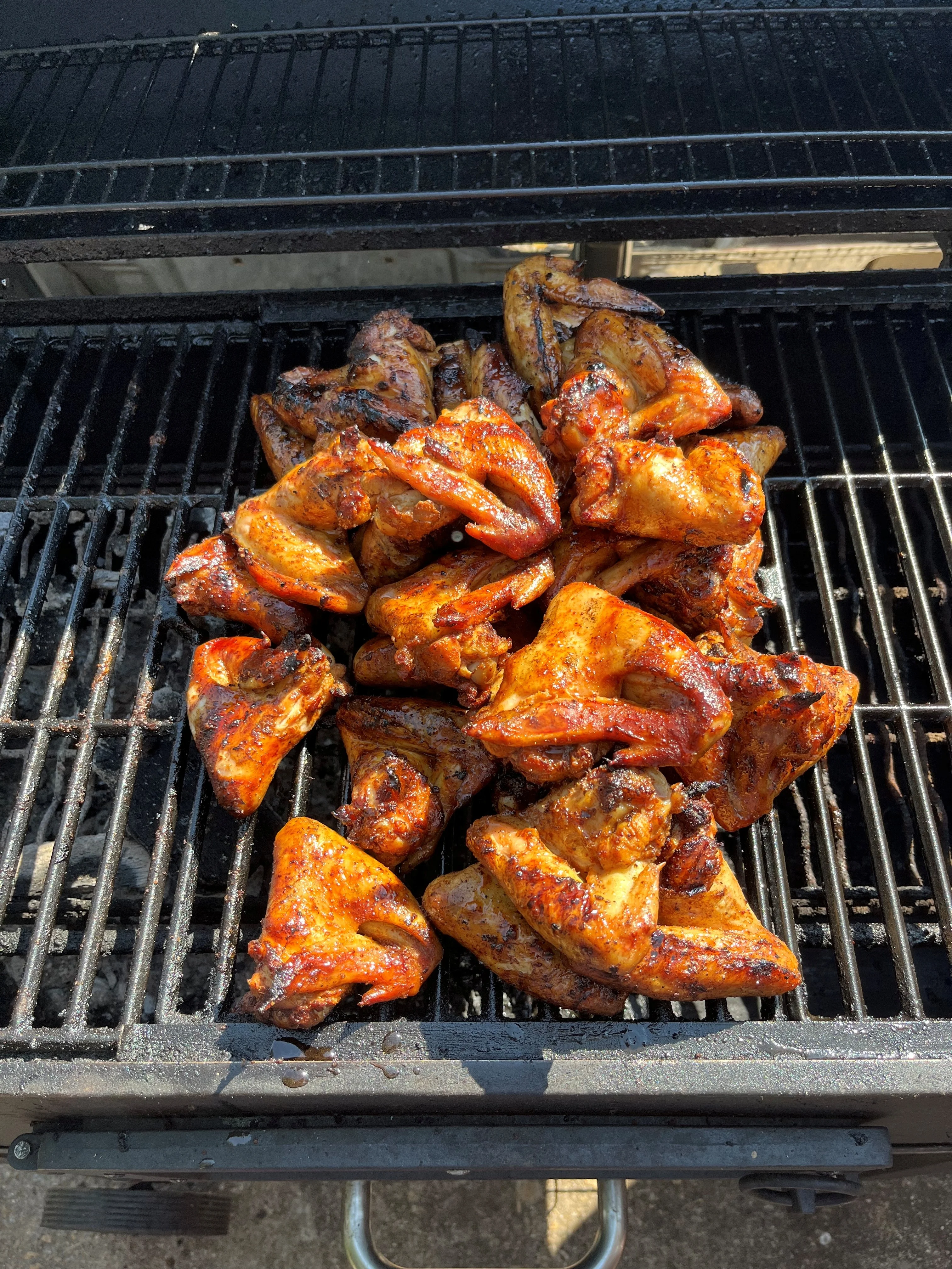 Grilled chicken wings with a rich, smoky glaze, arranged on the grill.