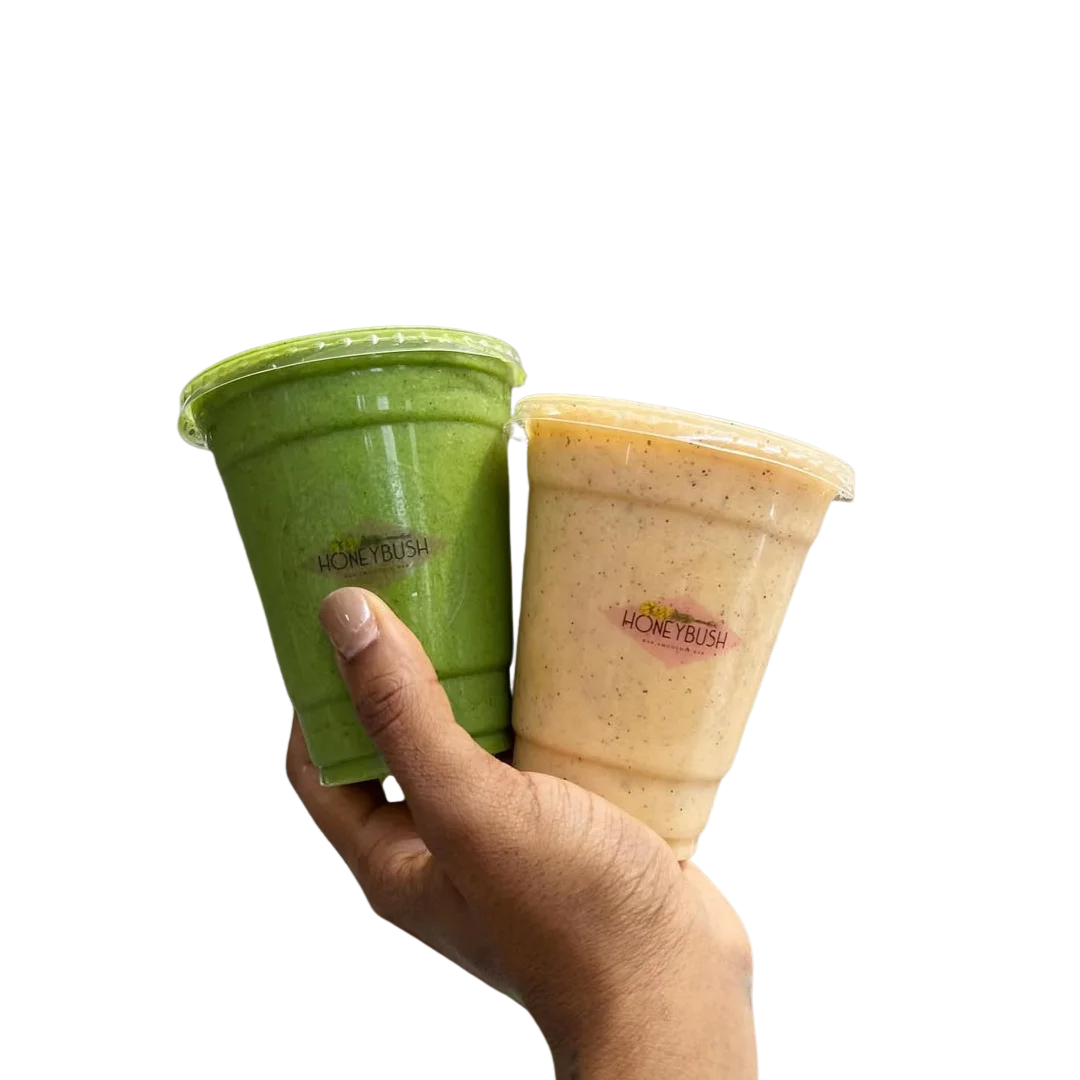 Hand holding two fresh smoothies from Honey Raw Smoothie Bar in Harrisburg, PA.