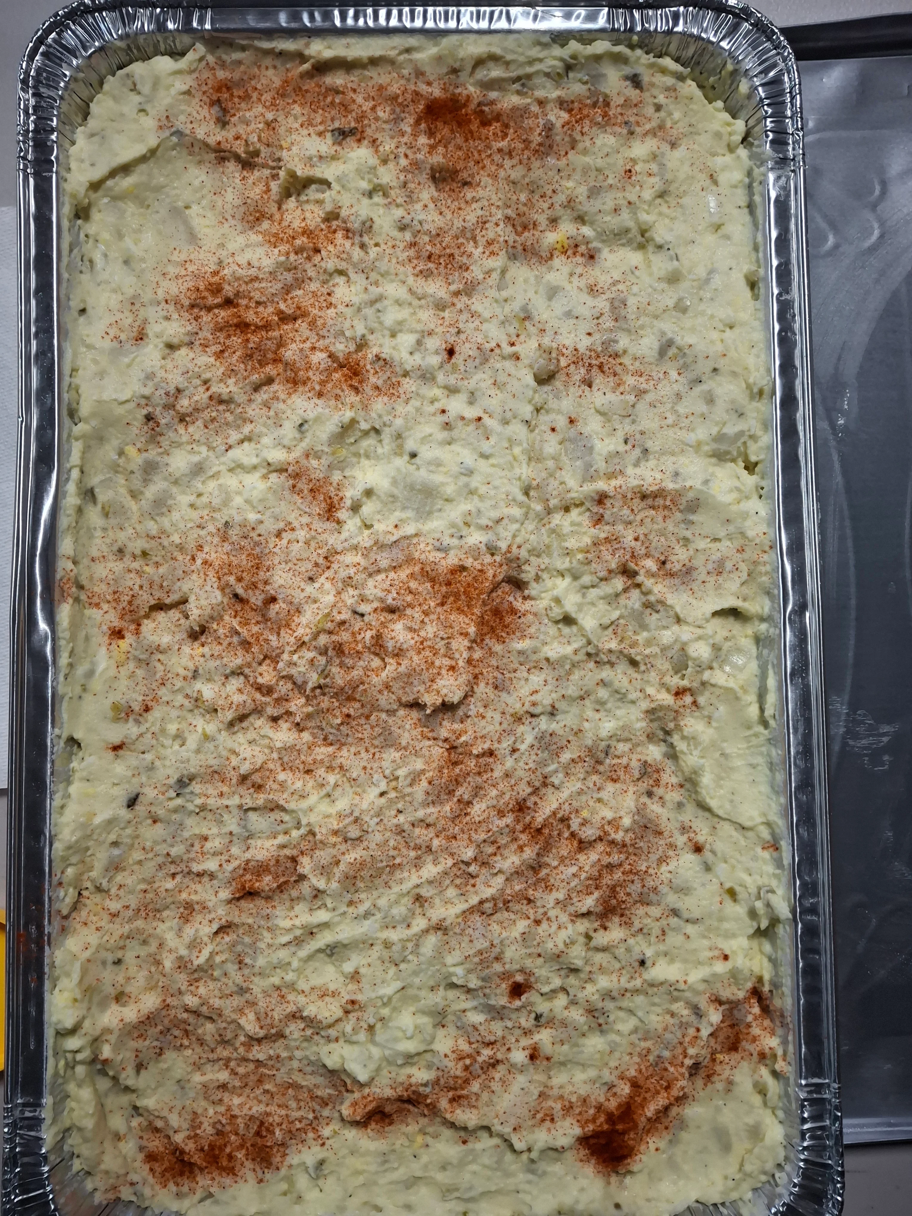 A tray filled with creamy mashed potatoes sprinkled with paprika.