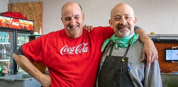 Two smiling chefs in a cozy restaurant kitchen
