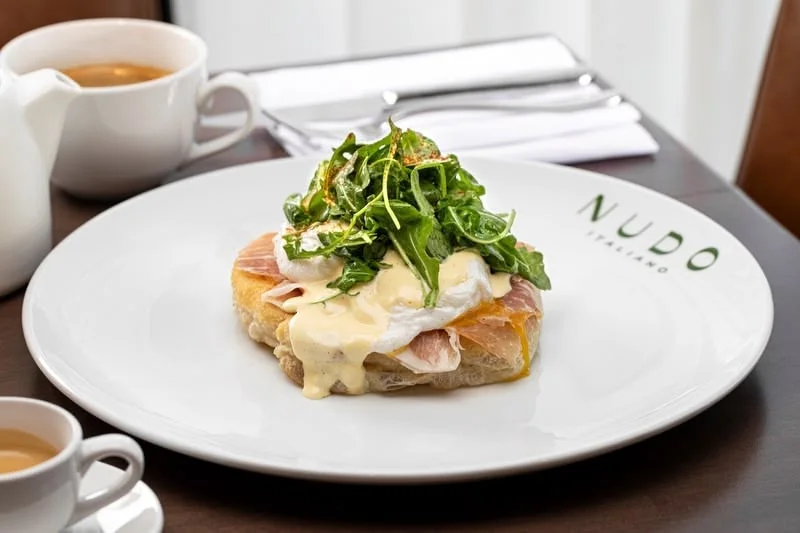 Eggs Benedict with arugula on toasted bread