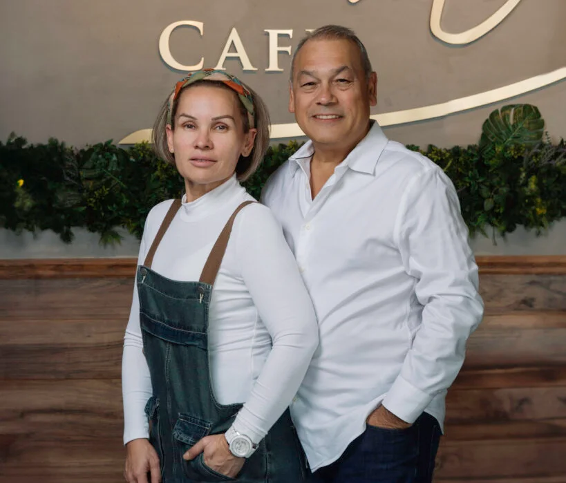 Owners of Aroma Cafe posing in front of their restaurant sign