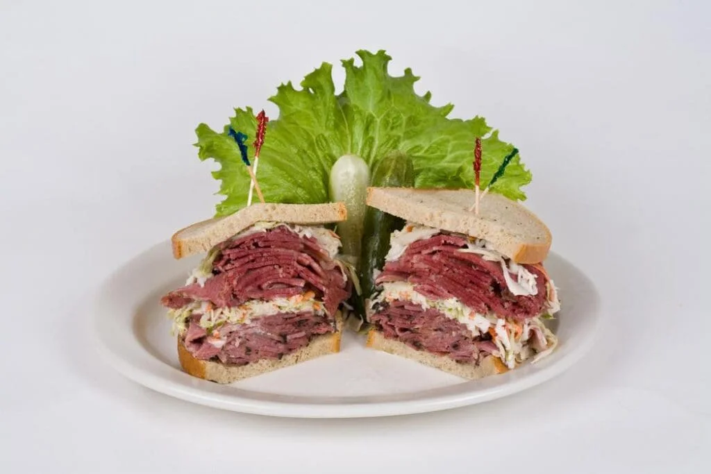 A hearty sandwich made with layers of pastrami or corned beef between slices of rye bread, showcasing its rich texture and flavor.