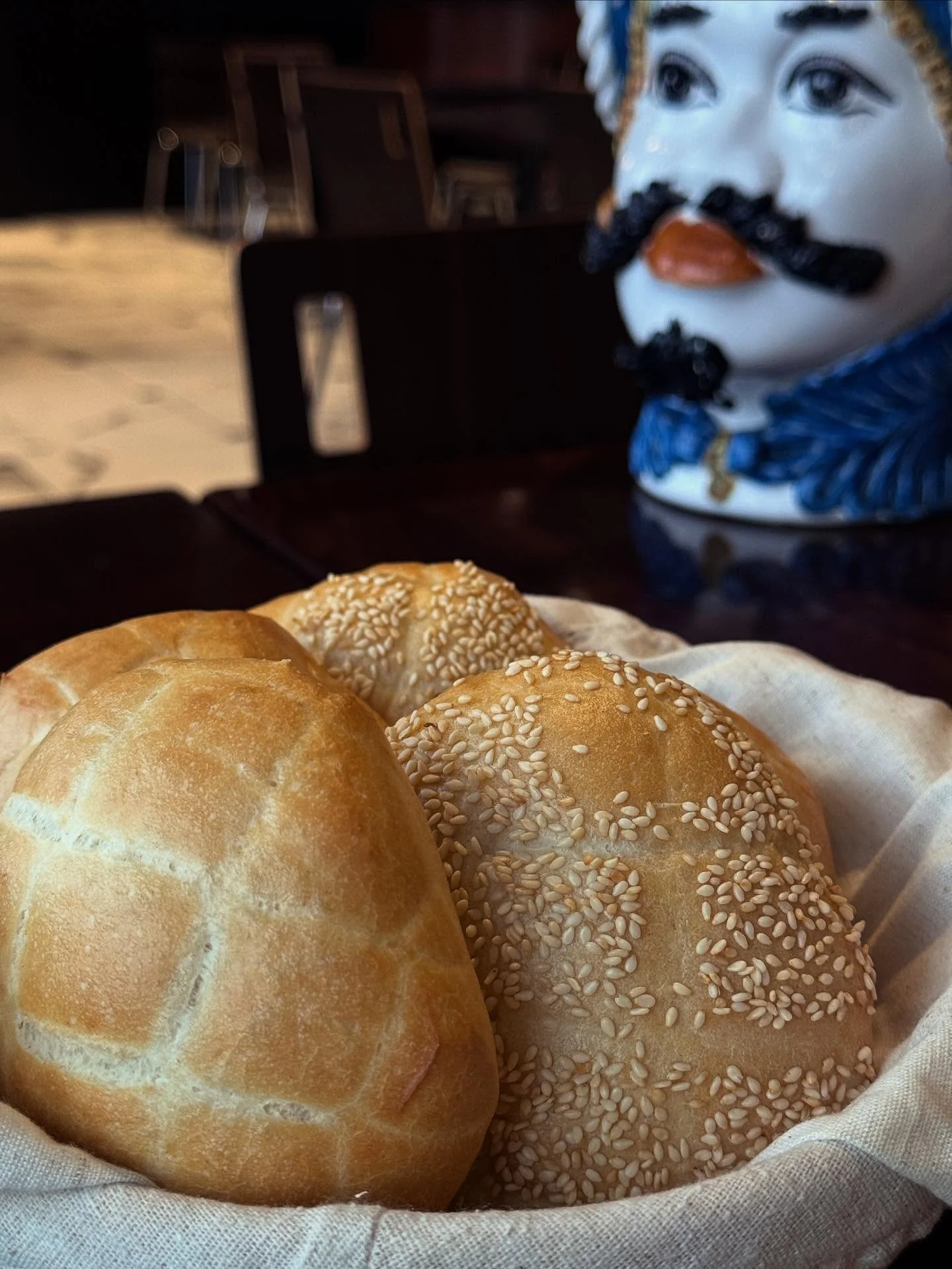 Freshly baked sesame bread rolls in a cozy restaurant setting