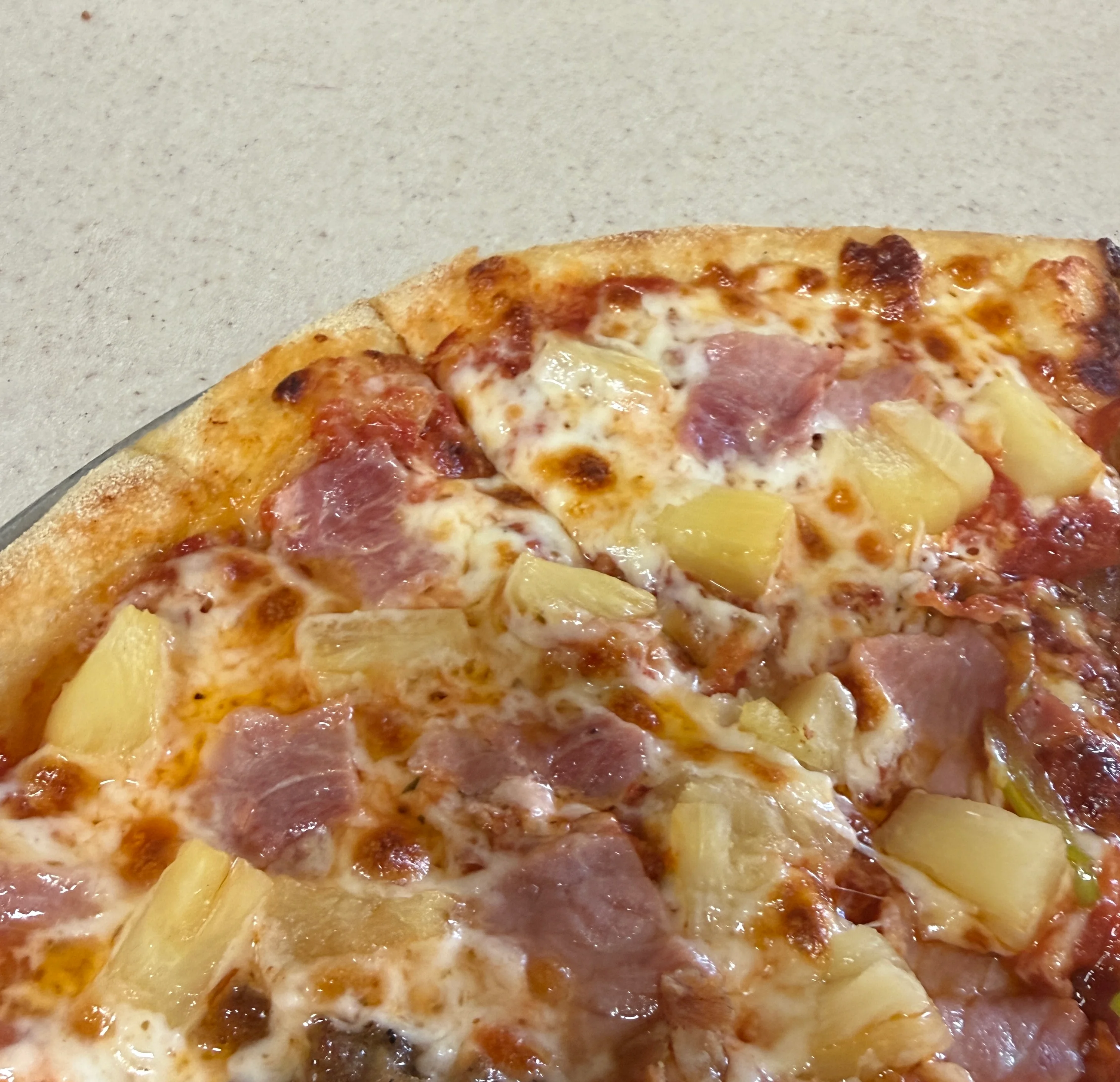 Hawaiian pizza topped with ham and pineapple, served fresh from the oven