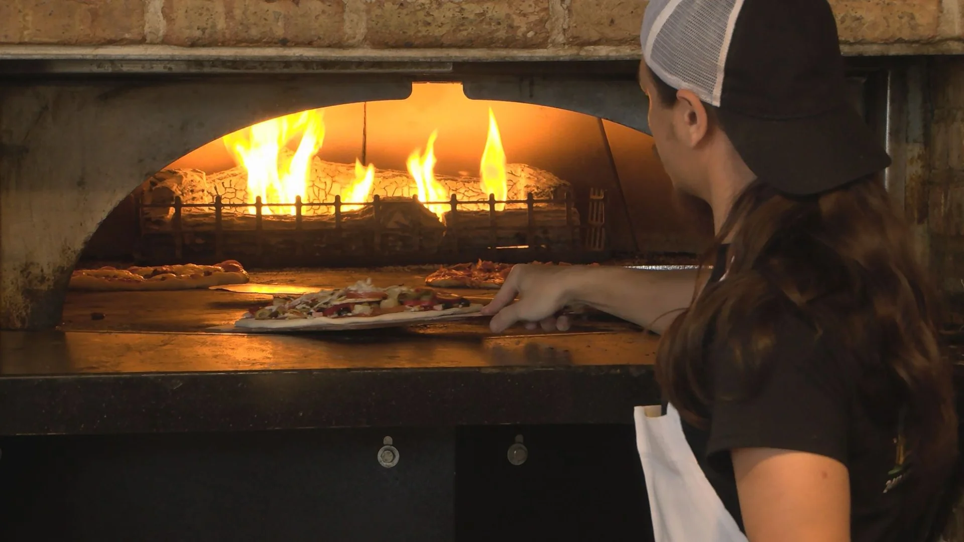 Chef placing Margherita pizza in a wood-fired oven