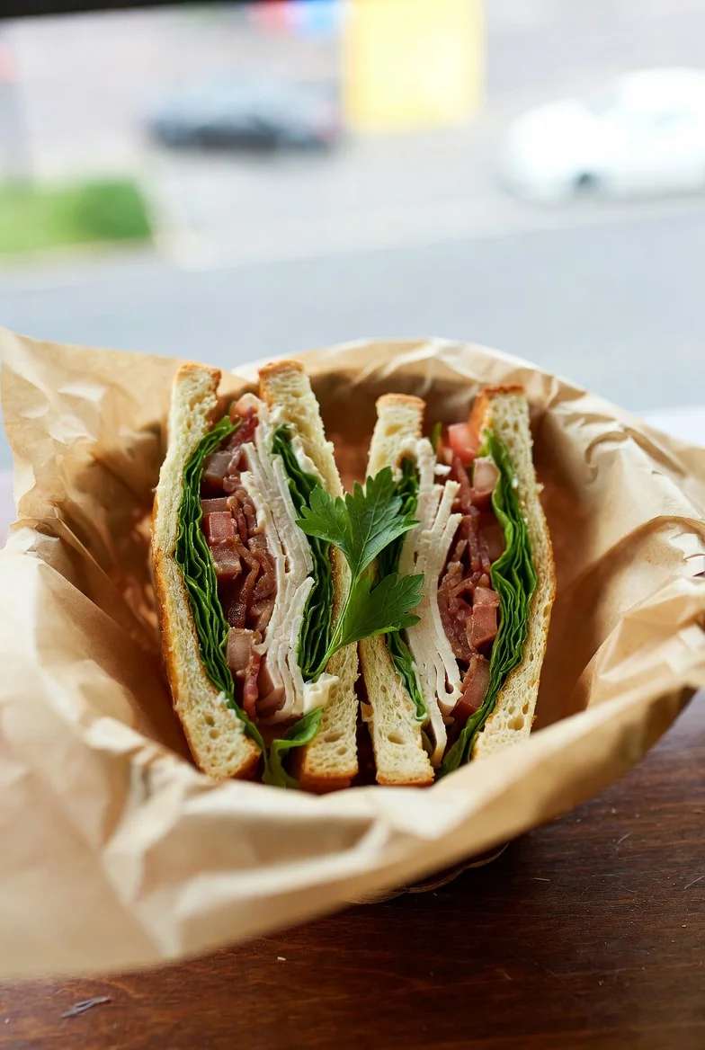 A sandwich with turkey, bacon, lettuce, and tomato, served in a basket.
