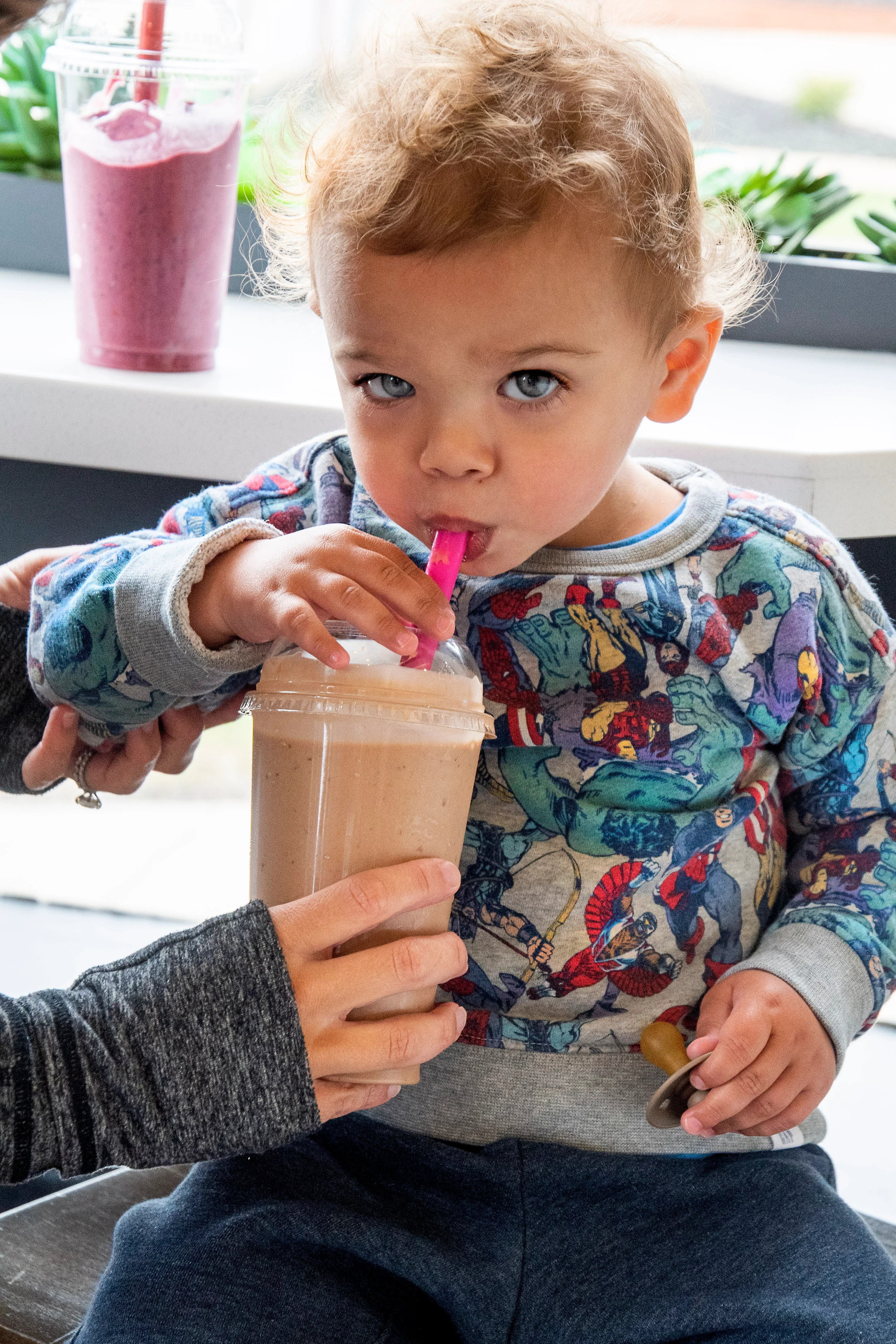 Child enjoying a smoothie in a cozy cafe setting