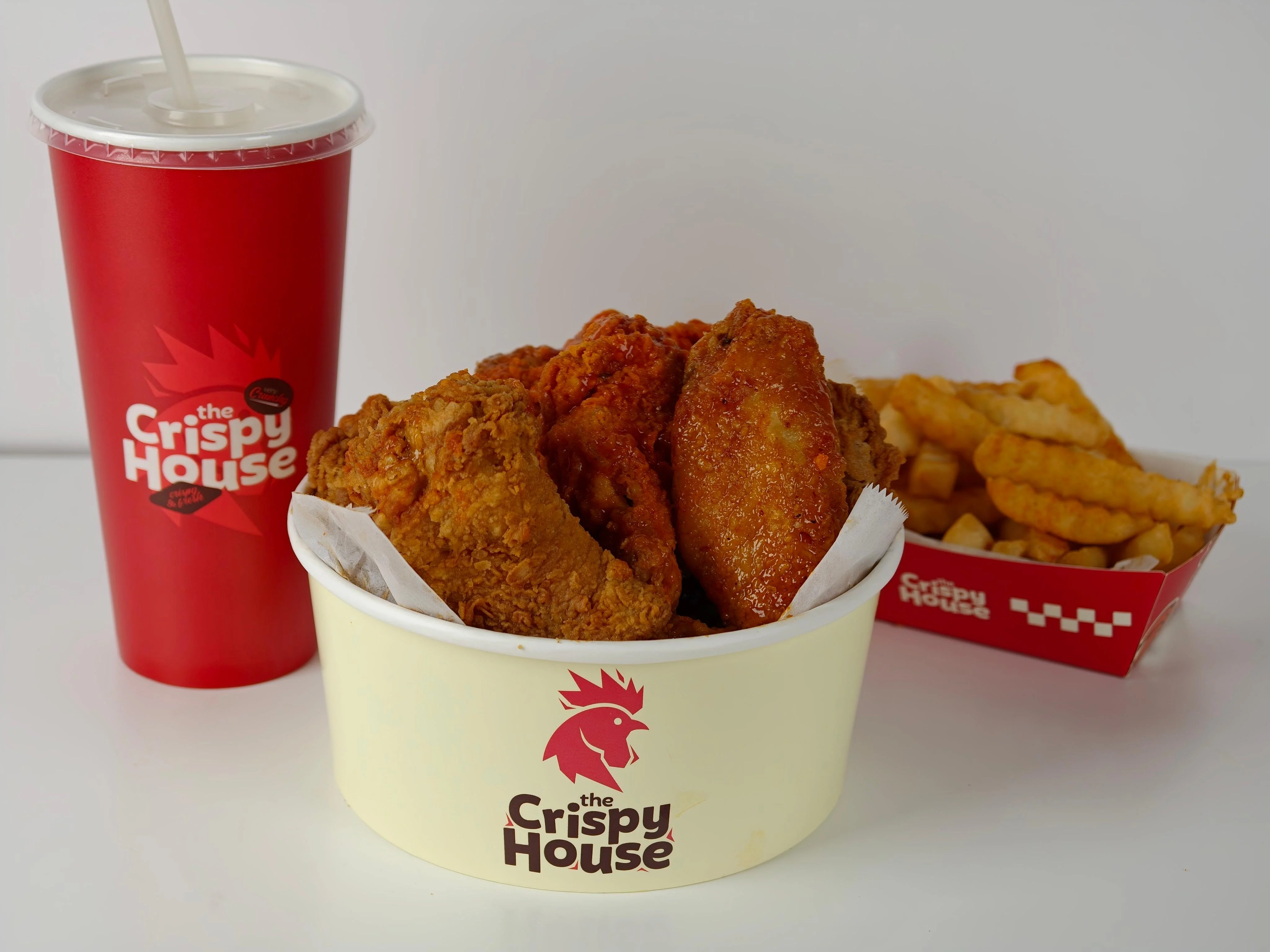 A meal featuring fried chicken pieces, a drink, and crinkle-cut fries, all presented in branded containers.
