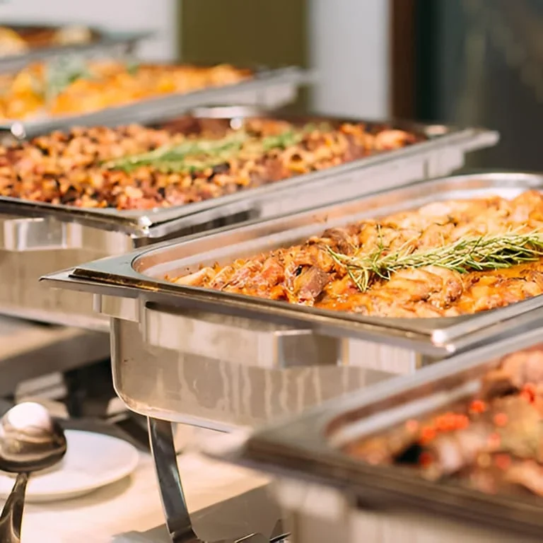 Buffet-style catering trays filled with freshly prepared Italian entrées ready for serving.