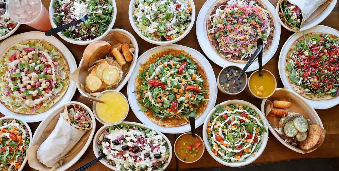 Table spread of flatbreads, bowls, burgers, and more