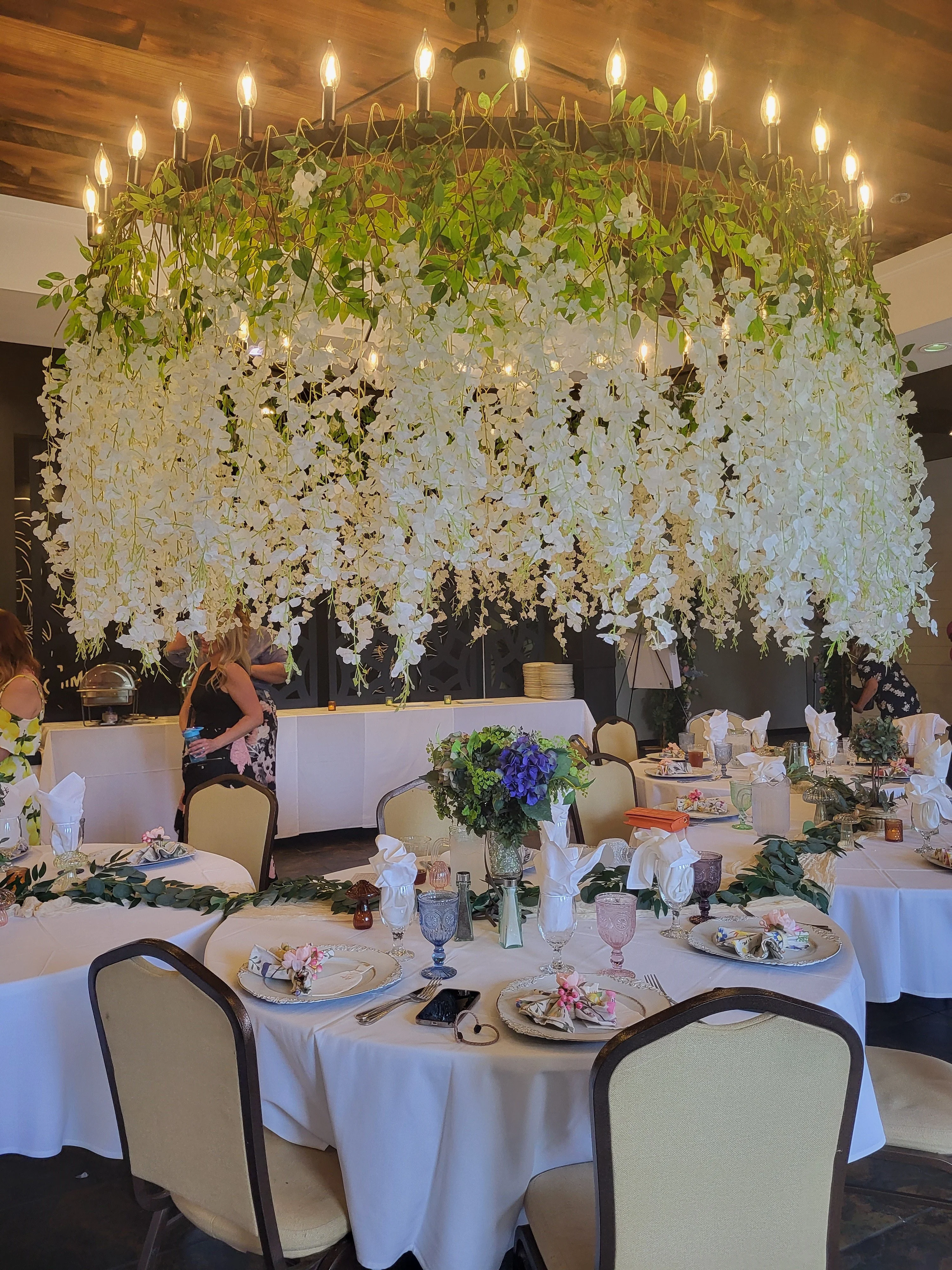 Elegant dining setup with floral chandelier and decorated tables